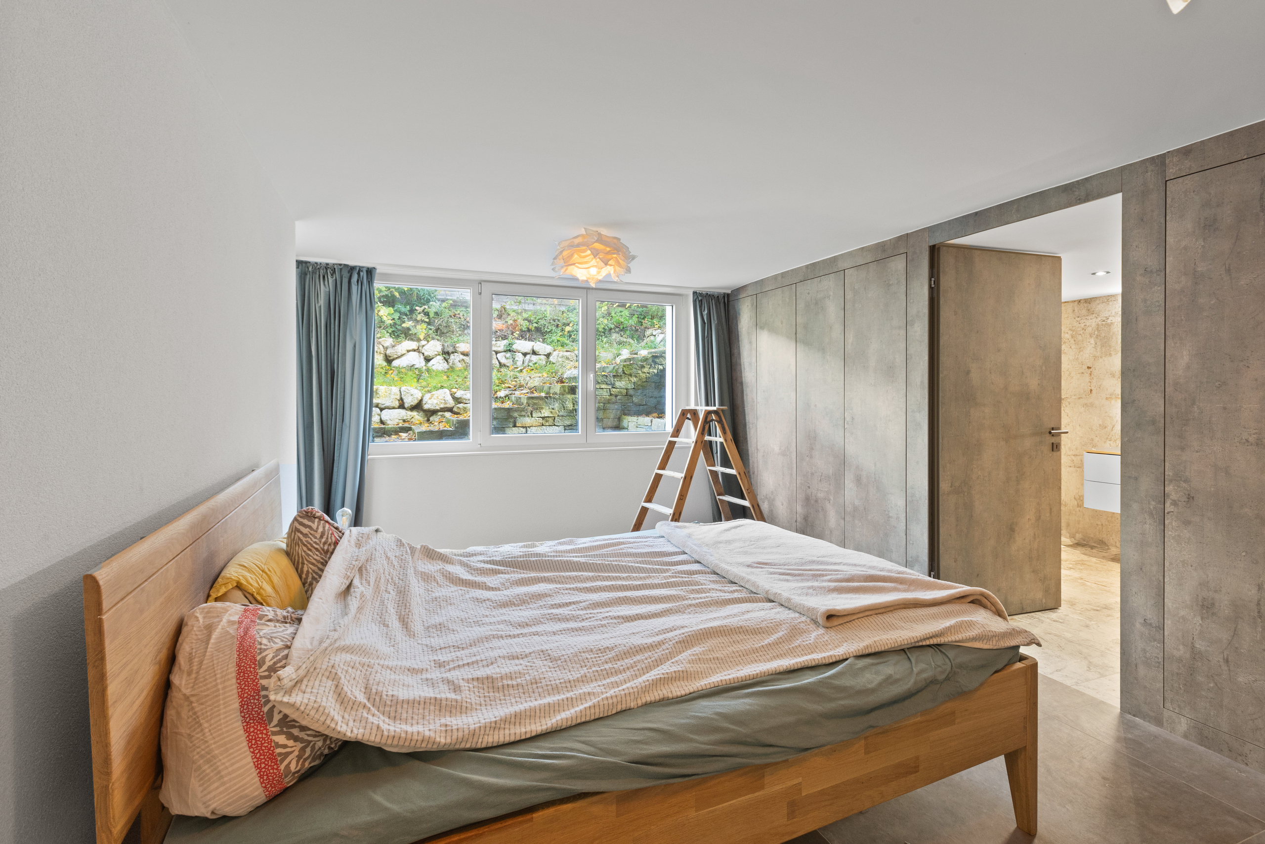 Modernes Schlafzimmer mit Naturholz-Bett und Blick ins Grüne