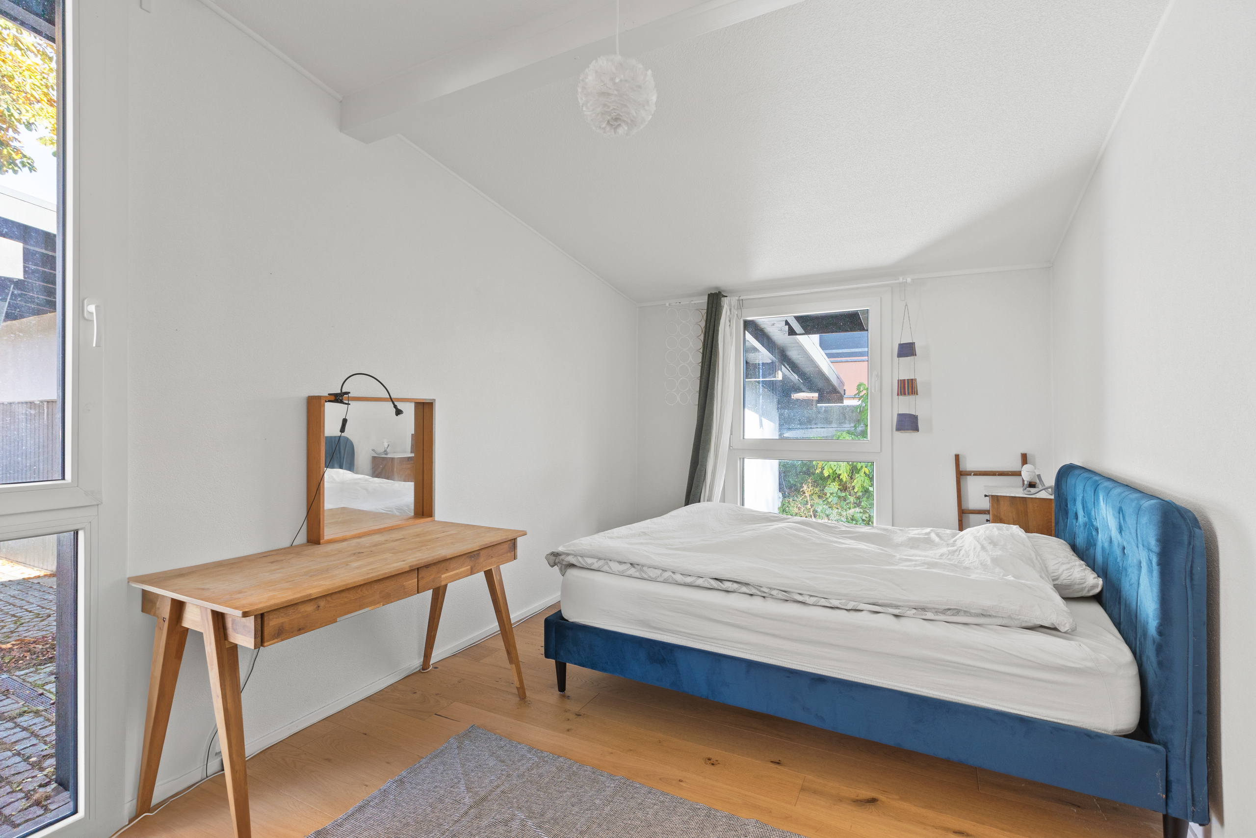 Helles Schlafzimmer mit blauem Bett und Holzmöbeln