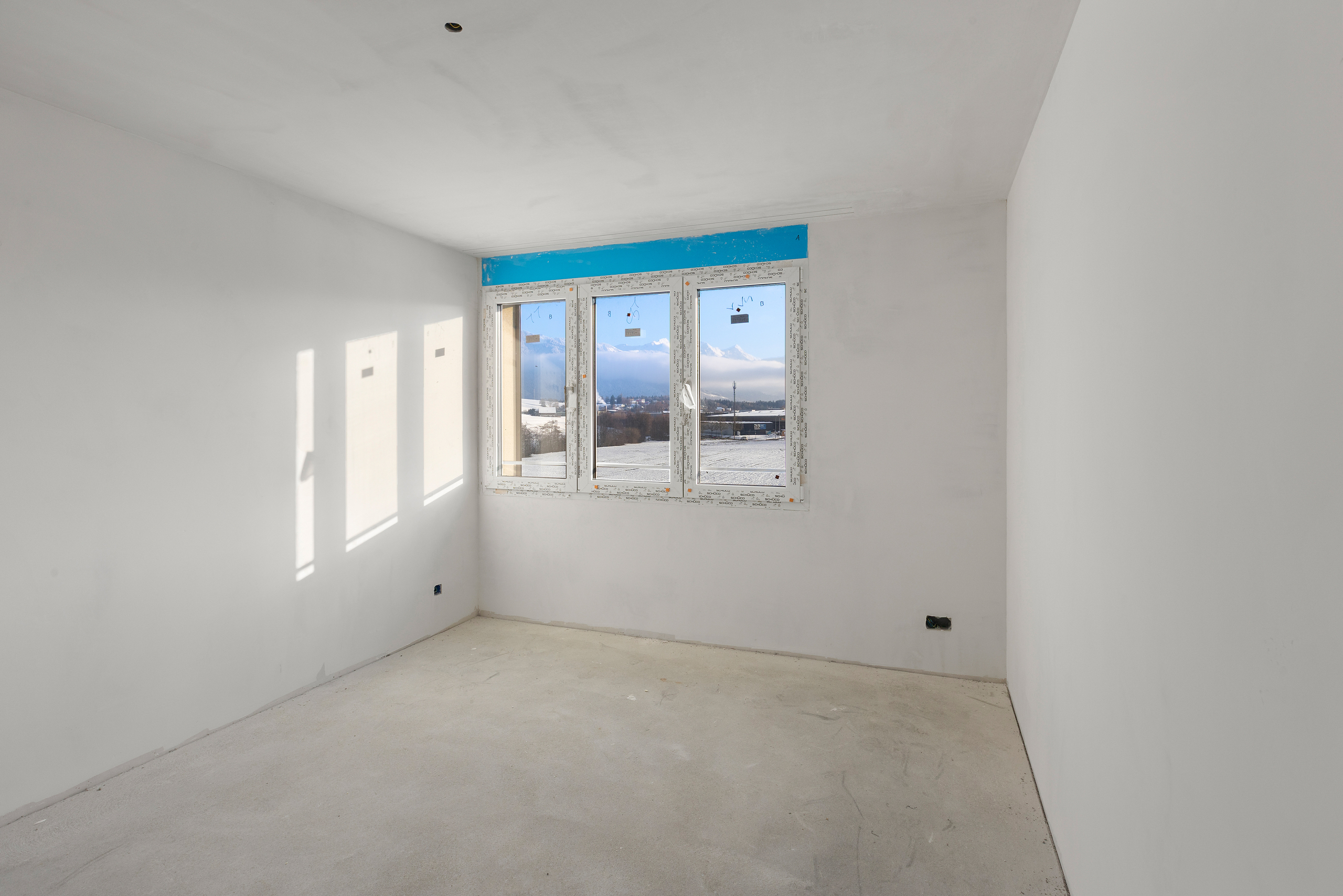 Rohbauzimmer mit Fenster und Bergblick