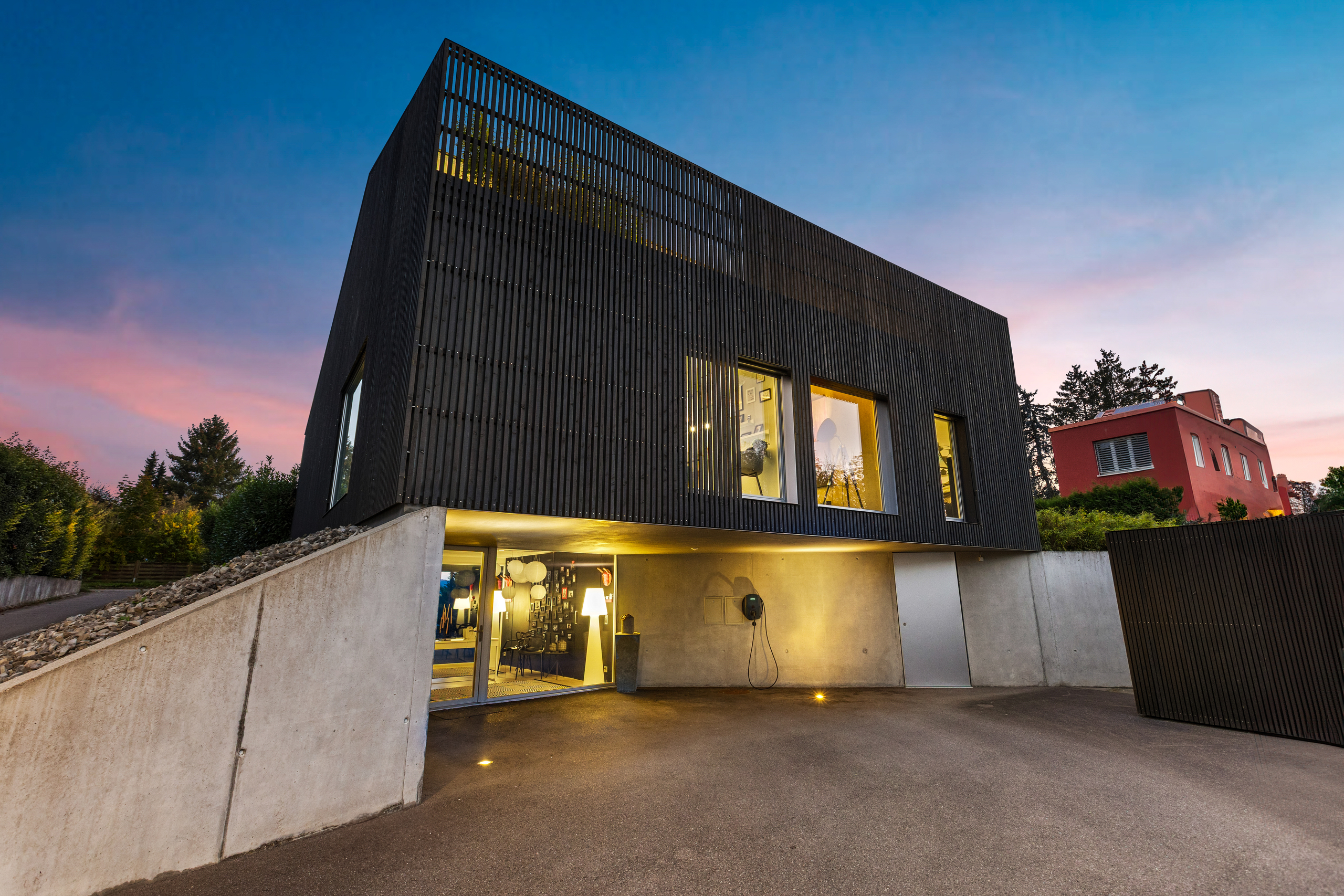 Modernes Einfamilienhaus mit dunkler Holzfassade bei Dämmerung