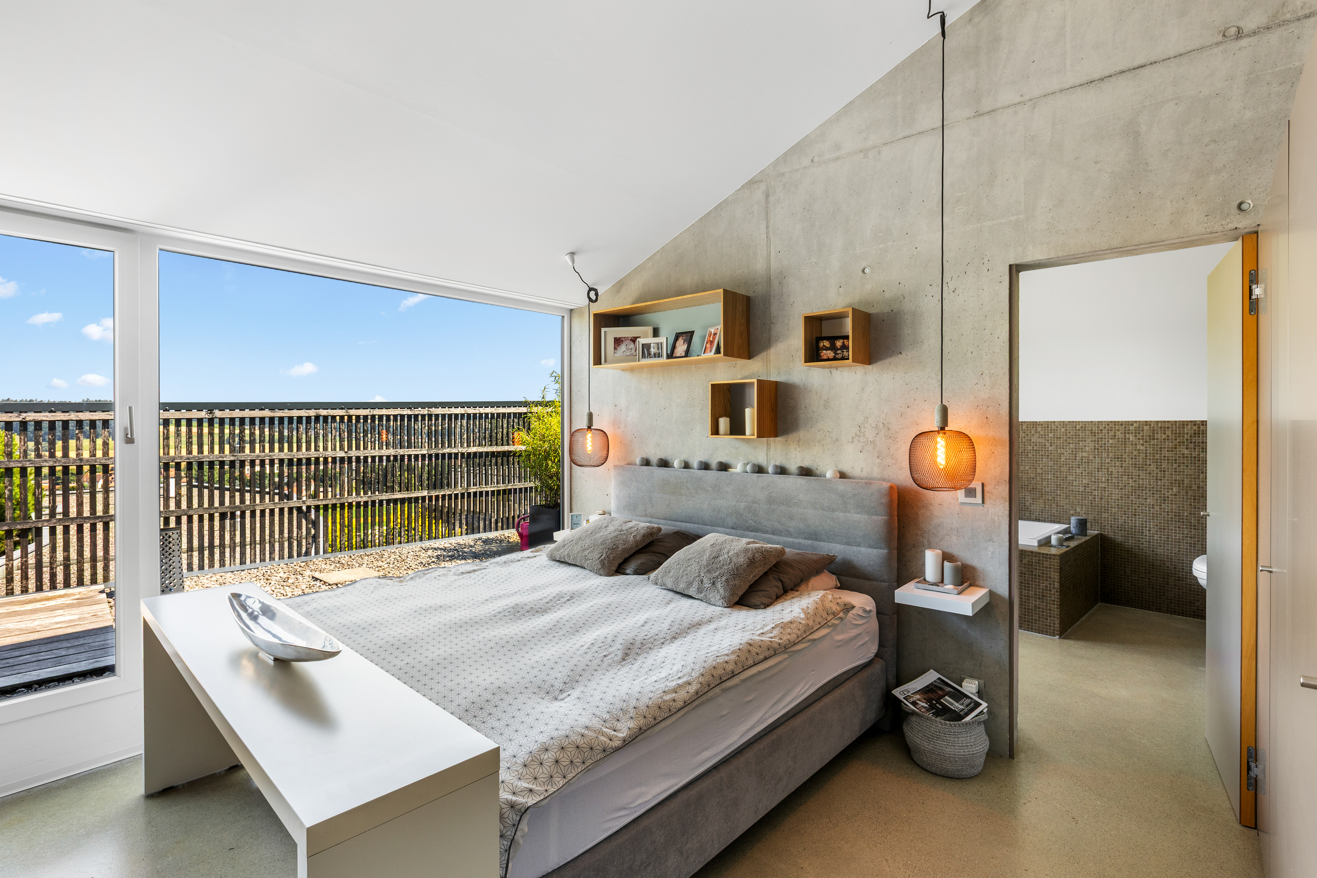 Modernes Schlafzimmer mit Betonwand und großem Fenster