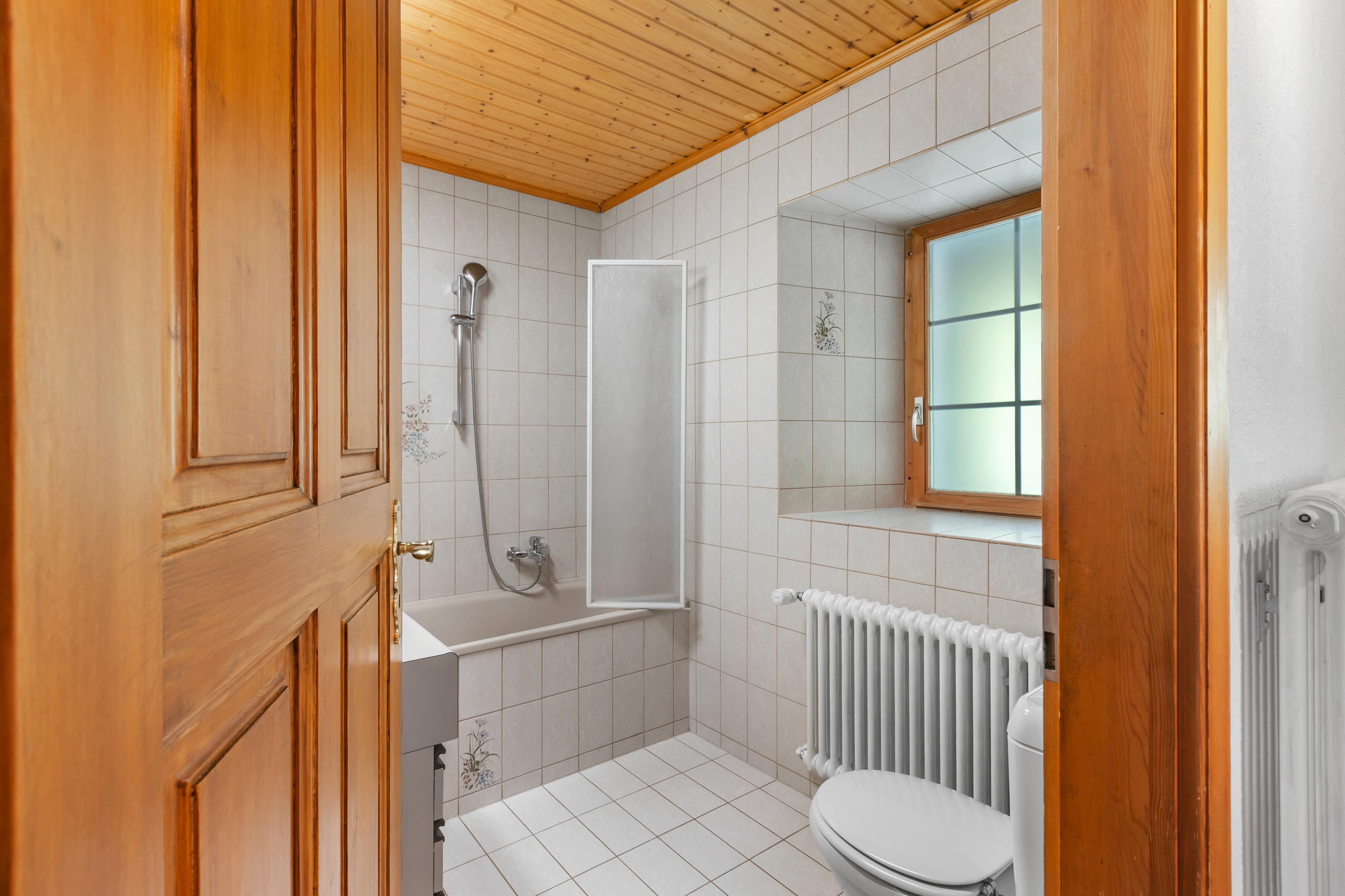 Badezimmer mit Badewanne und Holztür