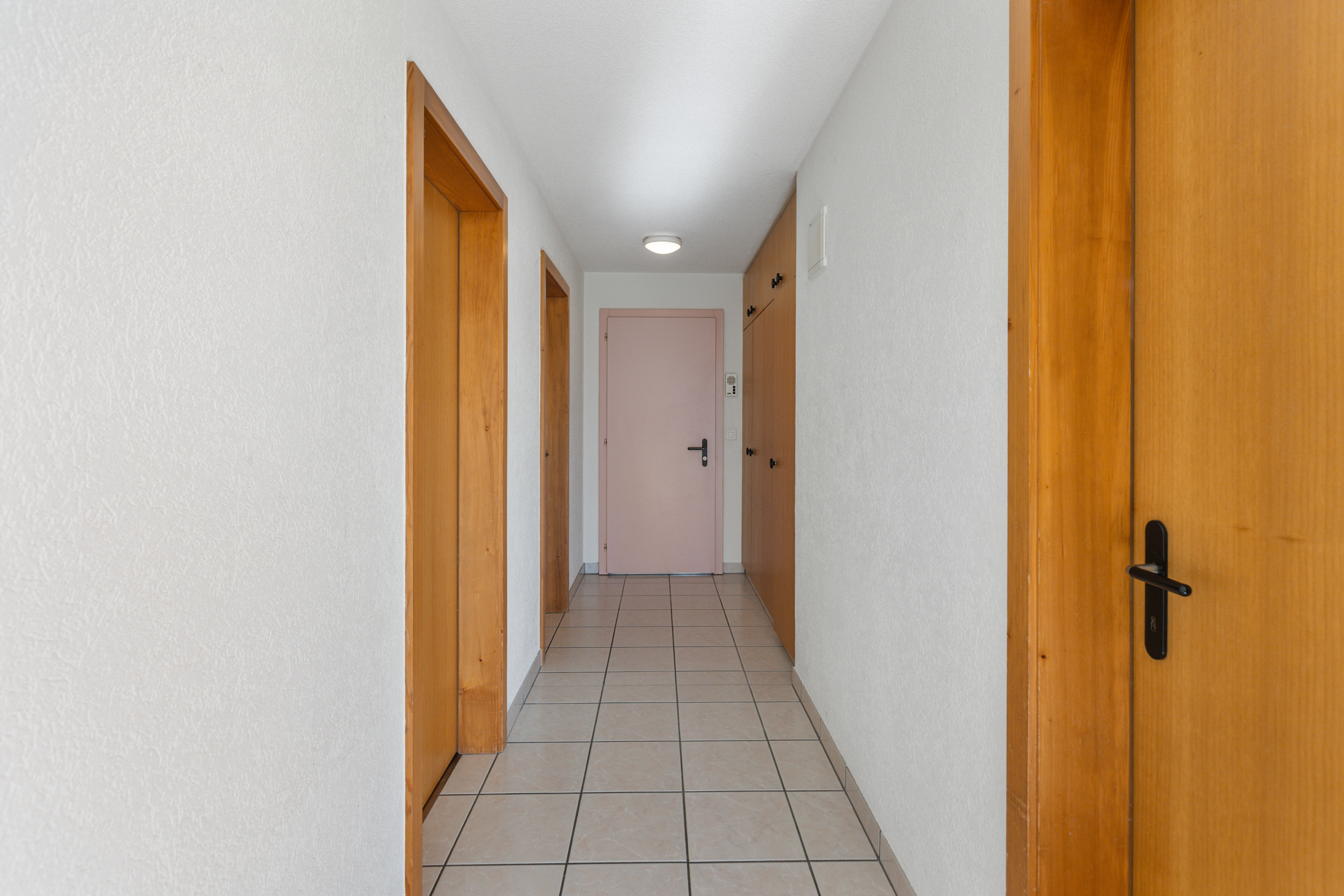 Heller Flur mit Türen und Fliesenboden