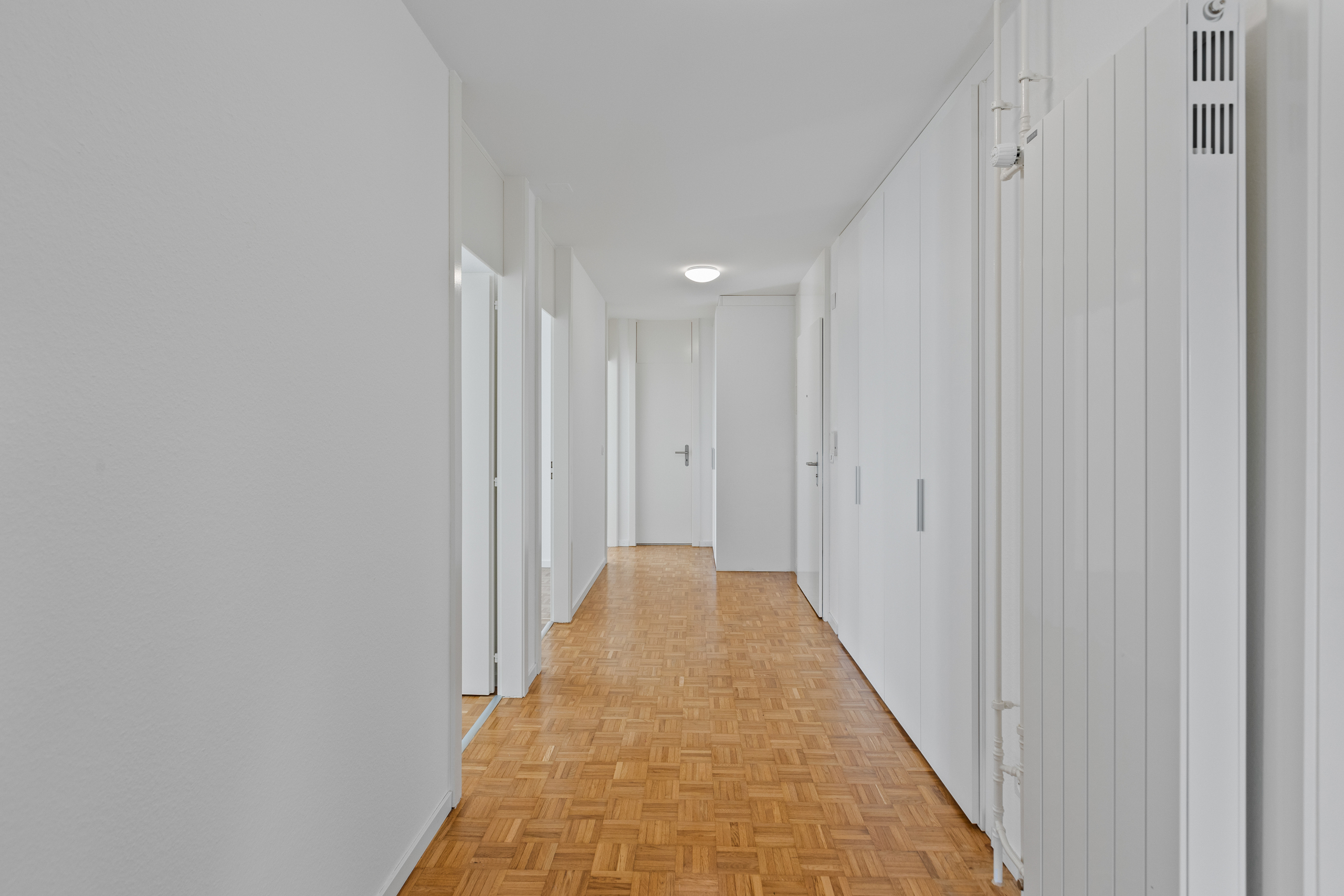 Heller, langer Flur mit Parkettboden