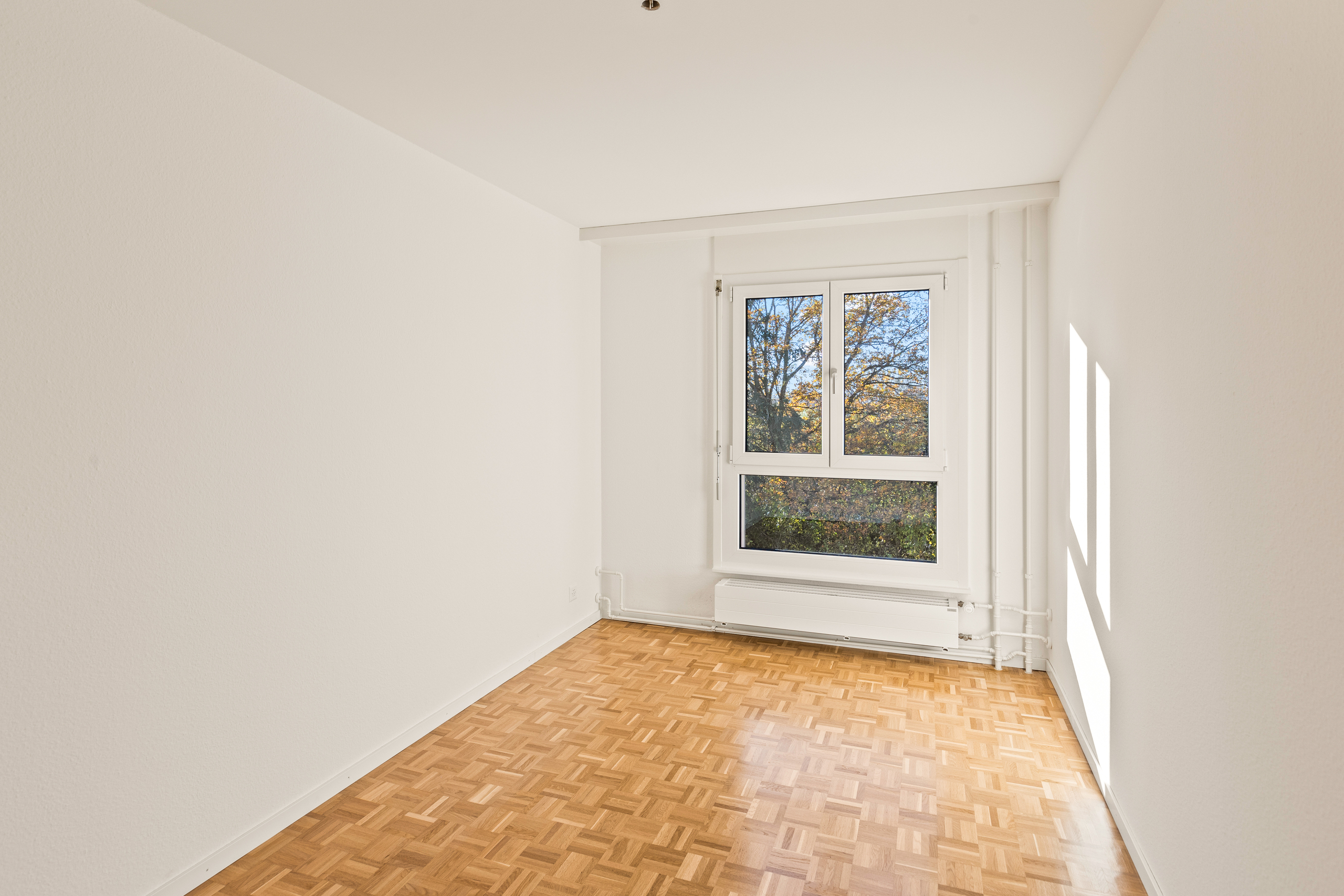 Heller leerer Raum mit Fenster und Parkettboden