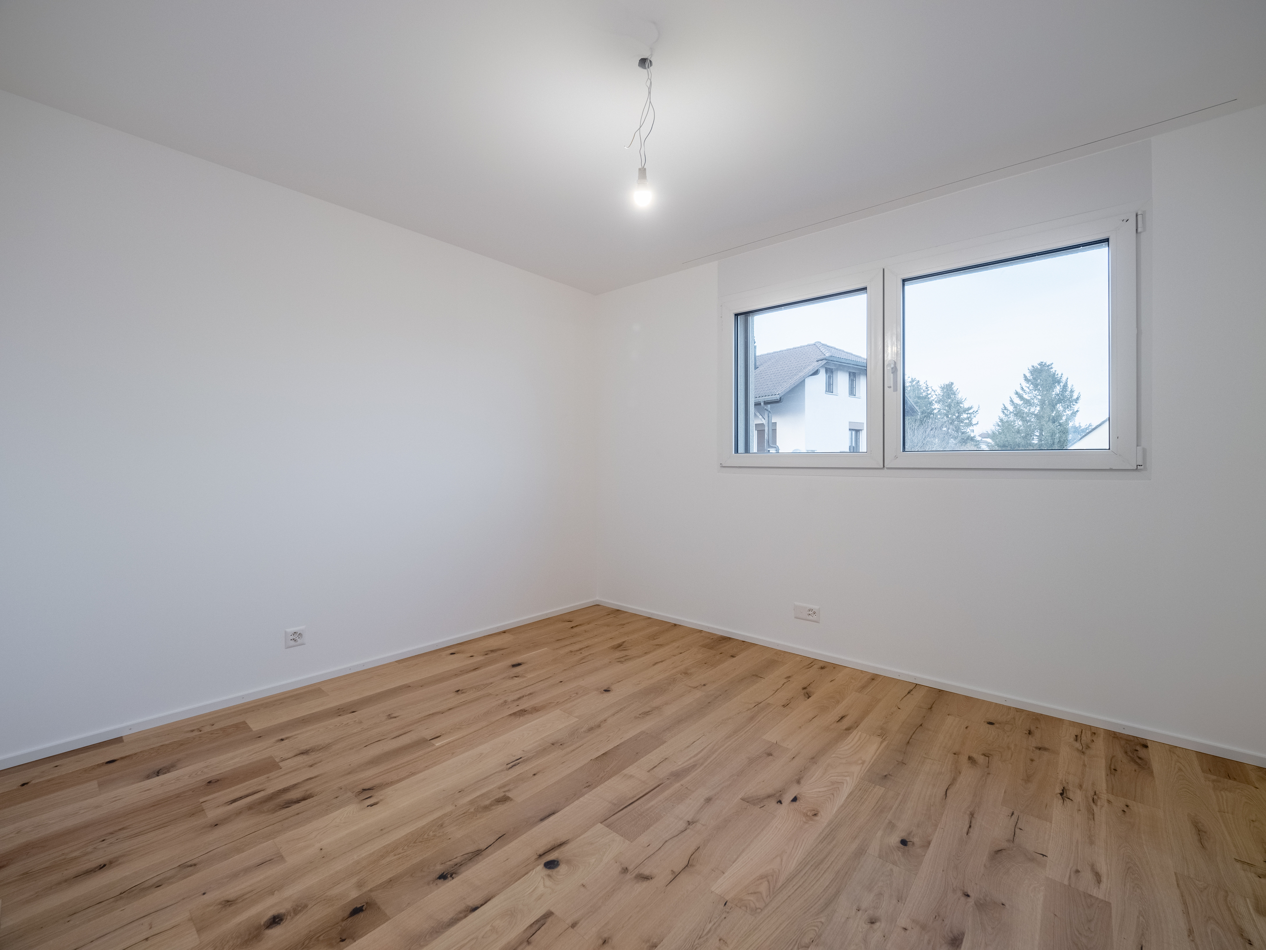 Leerer heller Raum mit Holzparkett und Fenster