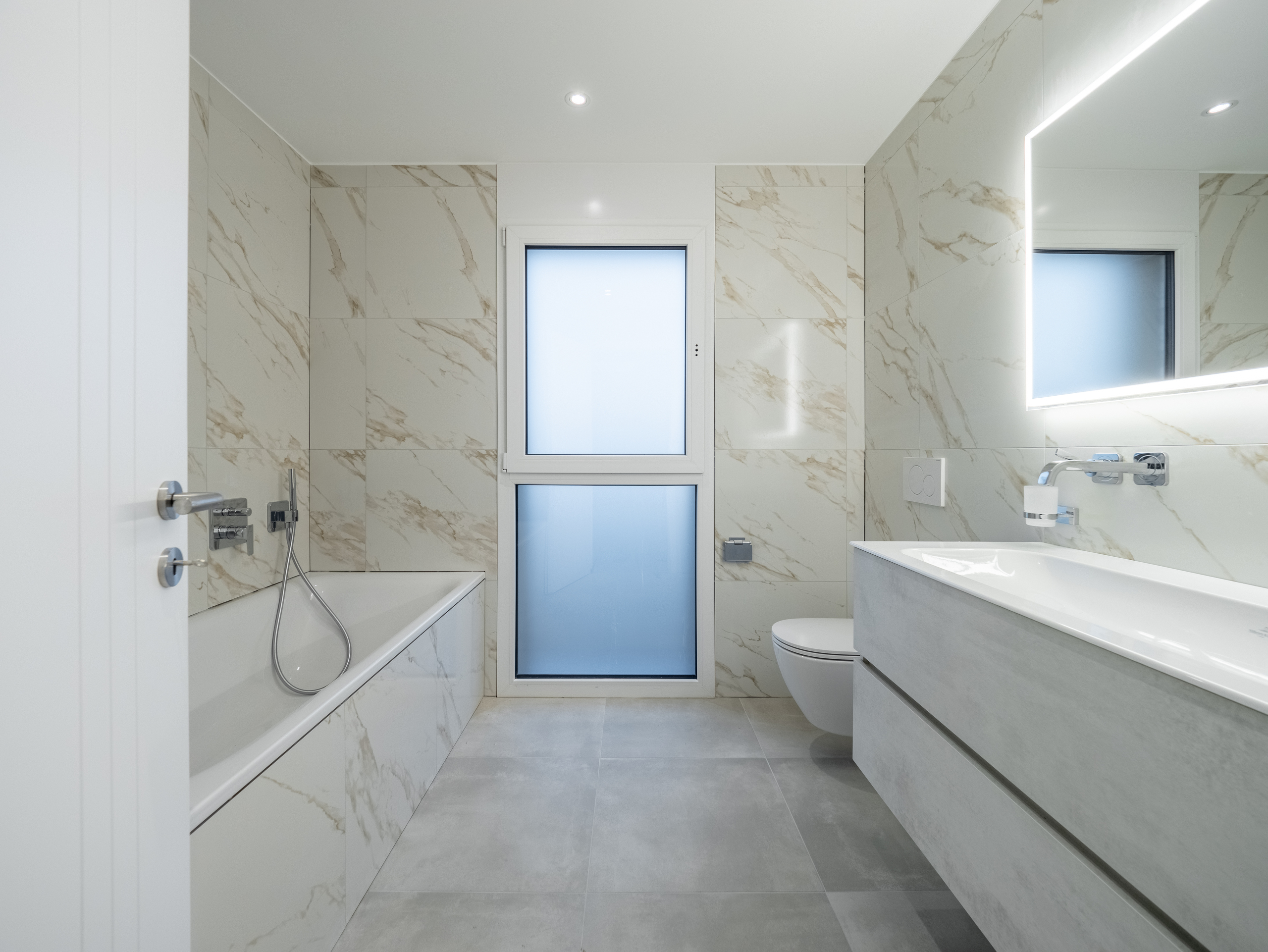 Modernes Badezimmer mit Badewanne, Waschtisch und Fenster