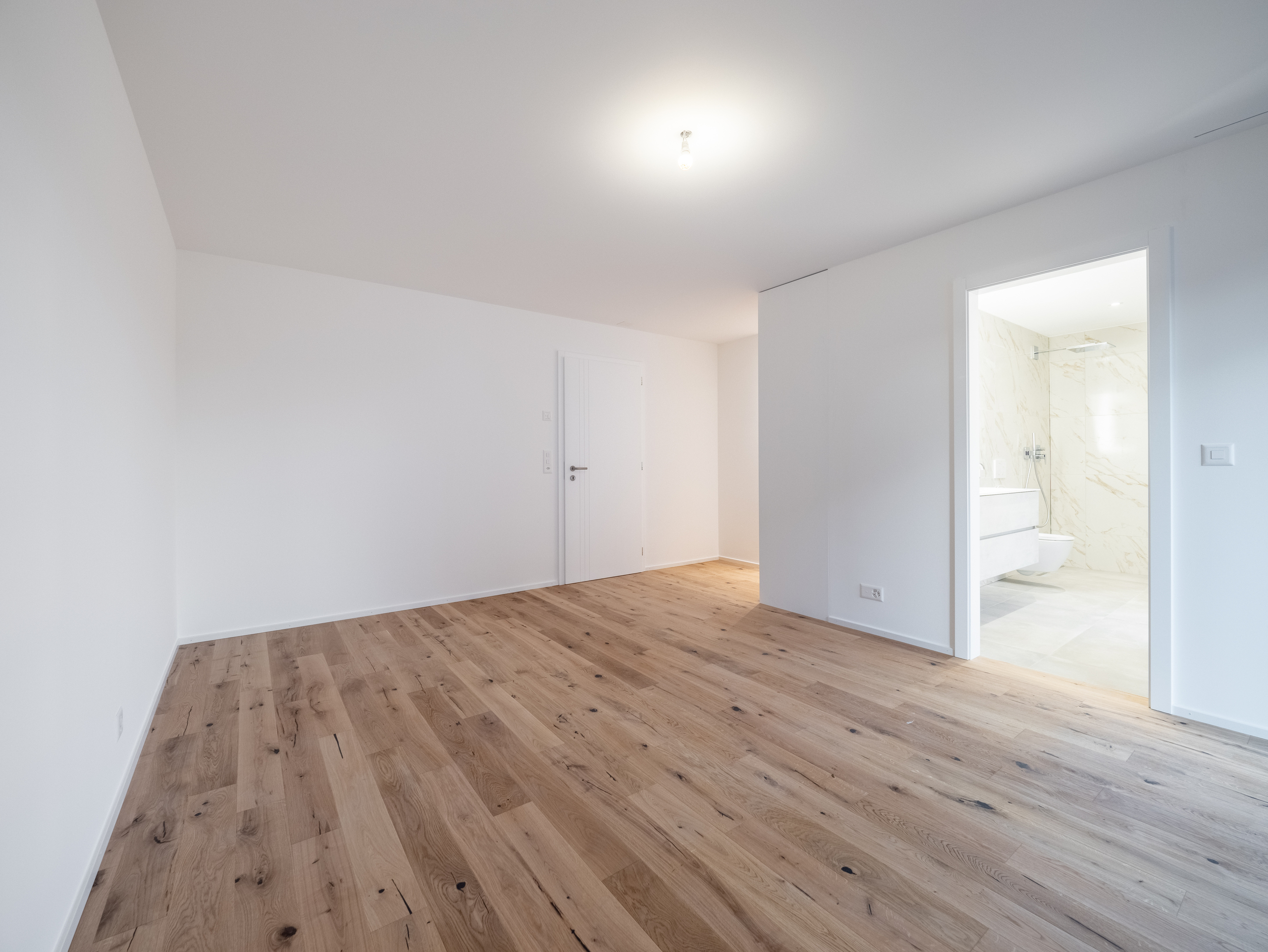 Helles, leer stehendes Schlafzimmer mit angrenzendem Bad