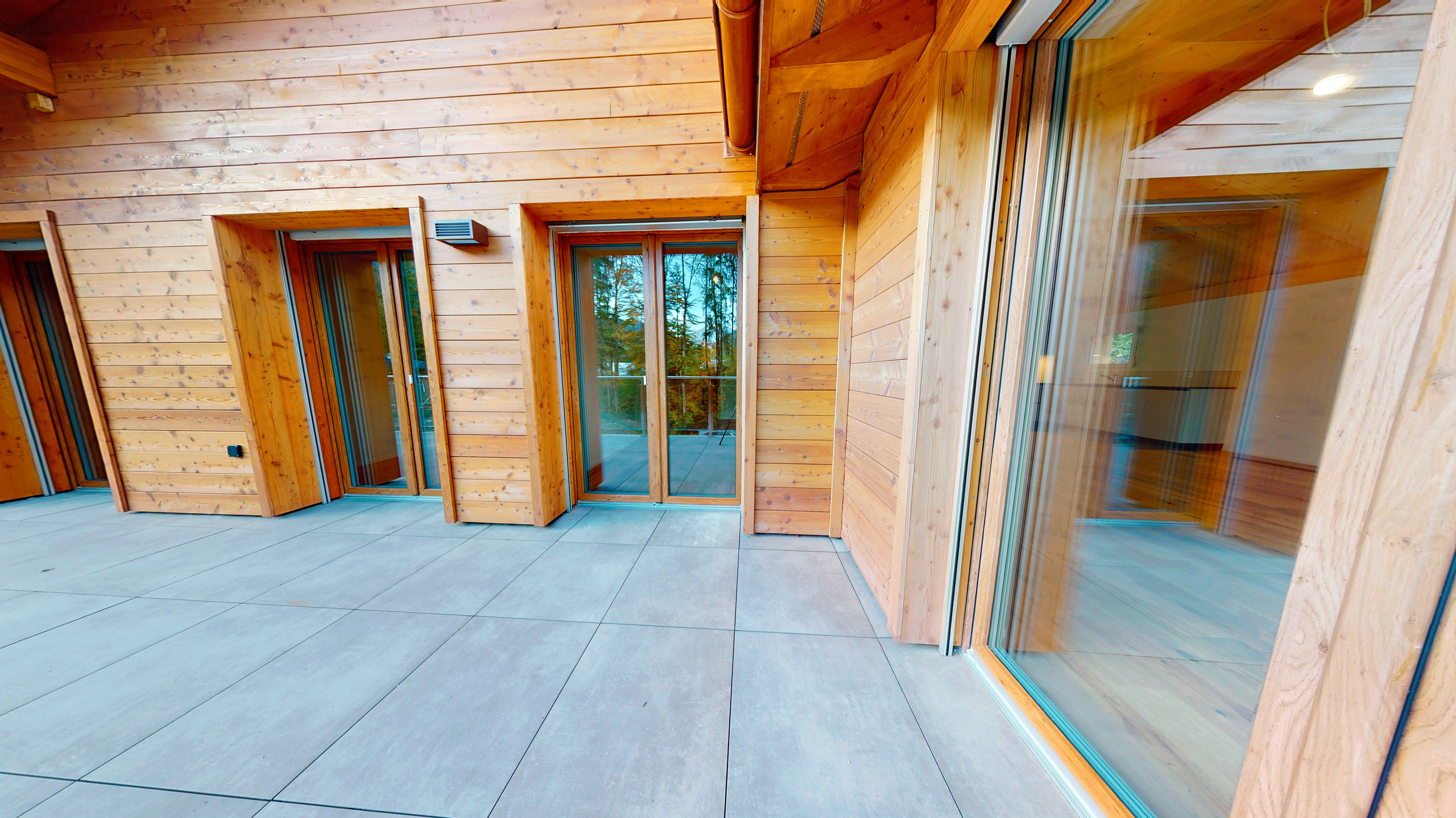 Holzterrasse mit großen Glasfronten