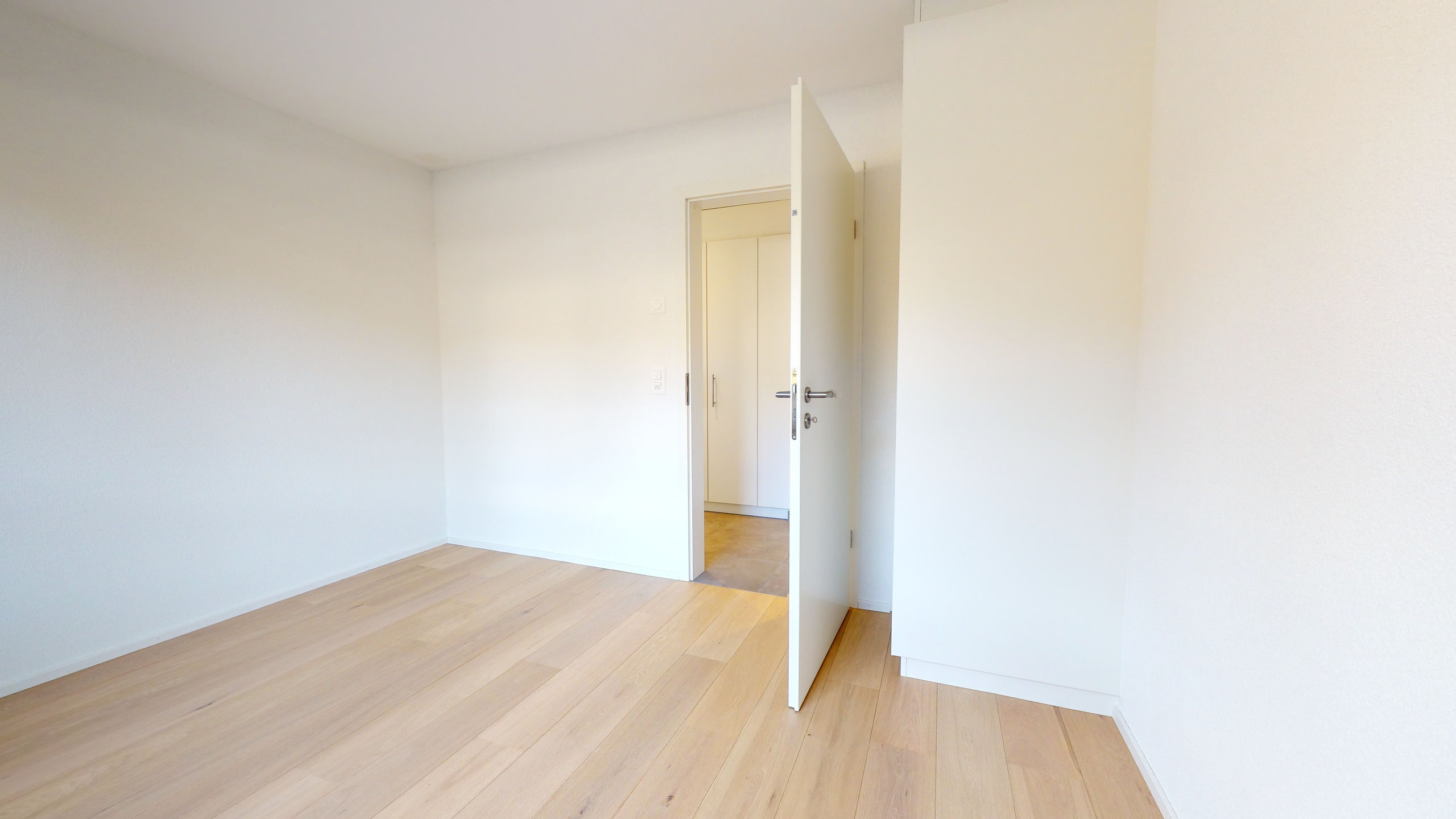 Helles, leeres Zimmer mit offenstehender Tür