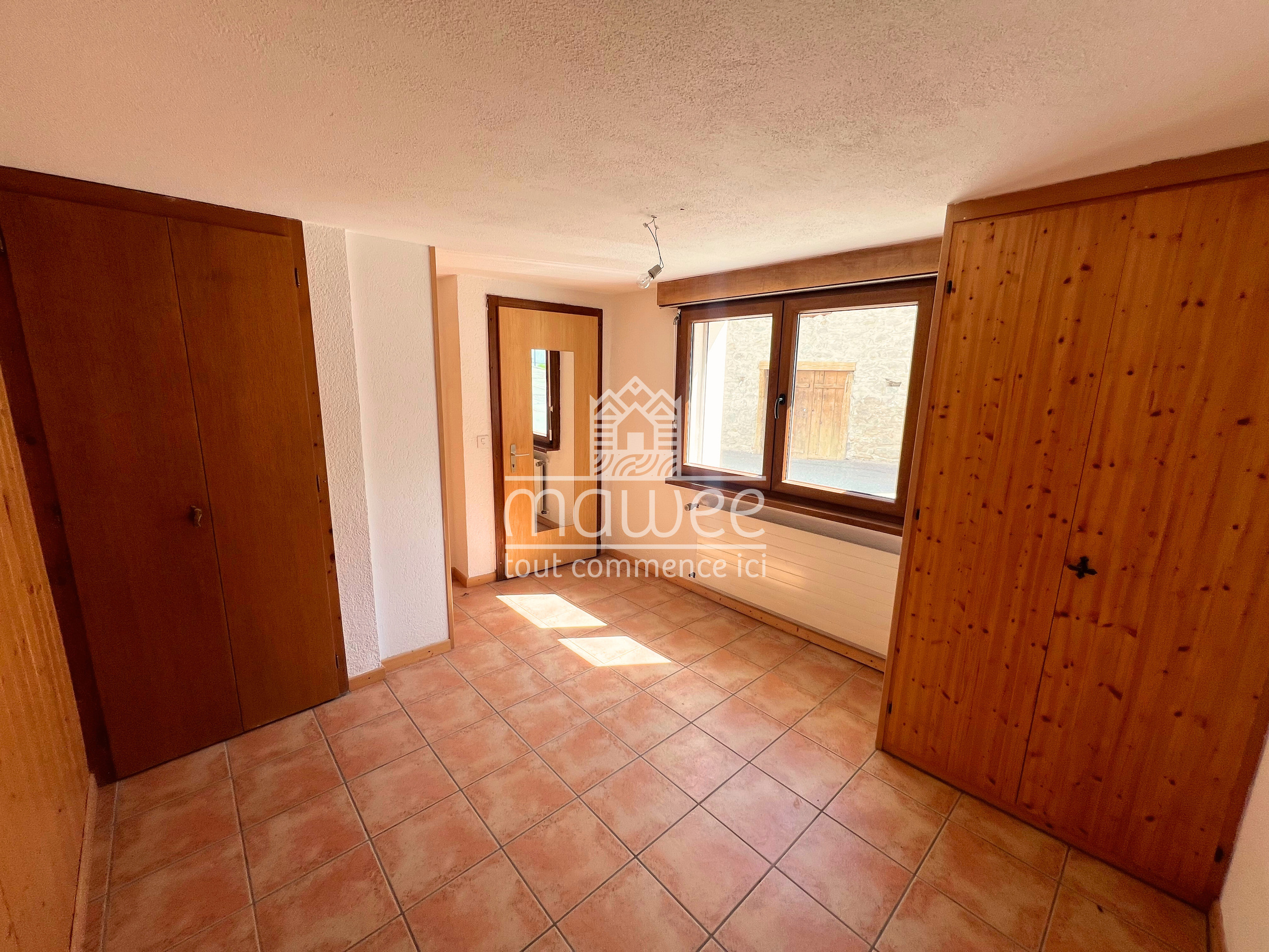 Heller, leerer Raum mit Fliesenboden und Holzdetails