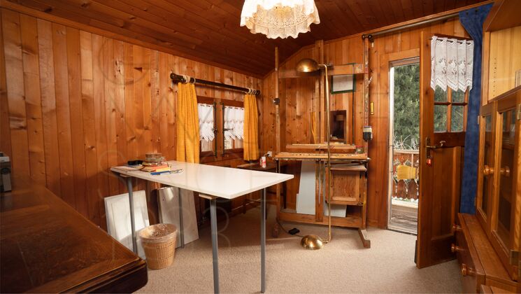 Holzverkleideter Raum mit Schreibtisch und Balkonzugang