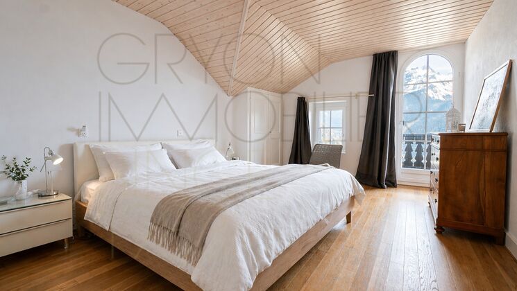 Helles Schlafzimmer mit Holzbalkendecke und Bergblick