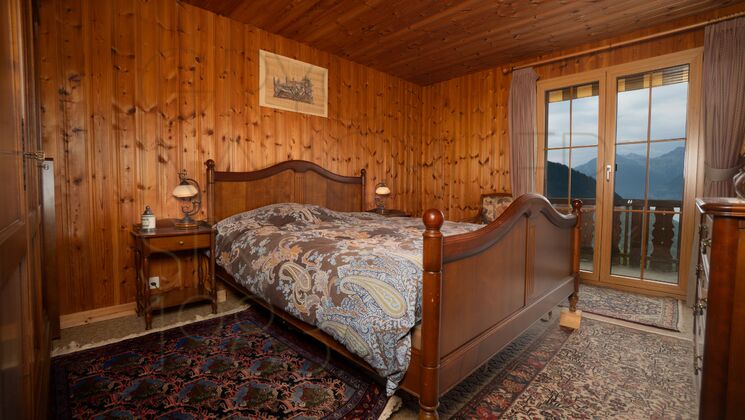 Rustikales Schlafzimmer mit Holzverkleidung und Bergblick