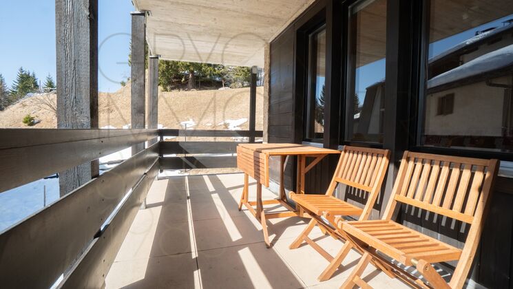 Überdachter Balkon mit Holzmöbeln