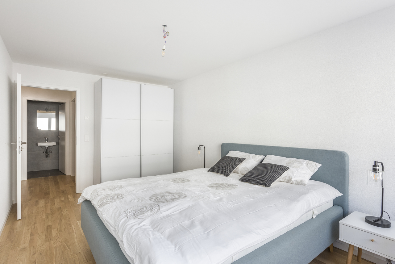 Helles Schlafzimmer mit Doppelbett und angrenzendem Bad
