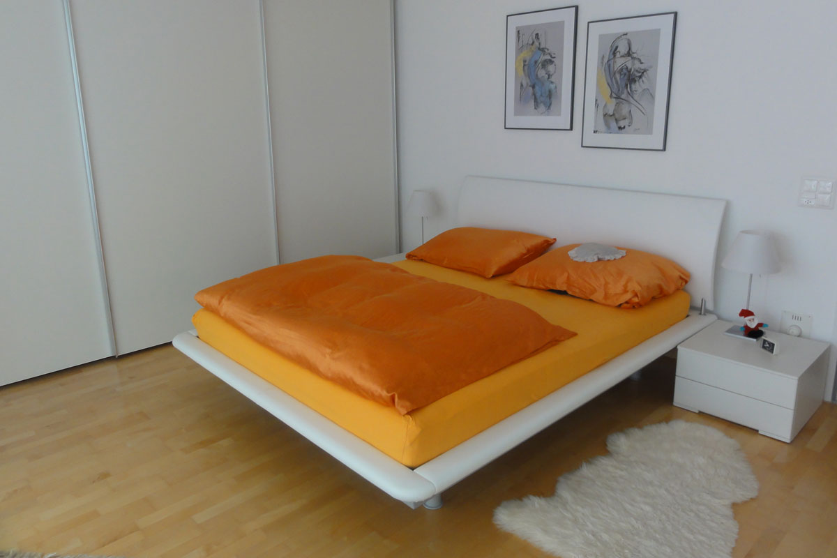 Modernes Schlafzimmer mit orangefarbener Bettwäsche