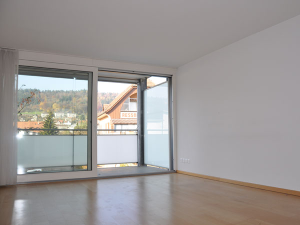 Leerer Wohnraum mit Balkon und Bergblick