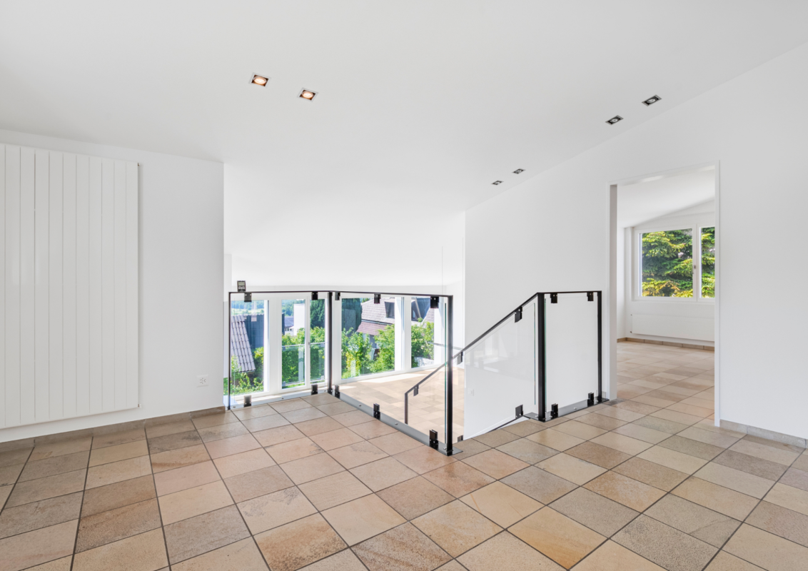 Heller Flurbereich mit Treppe und Glasgeländer