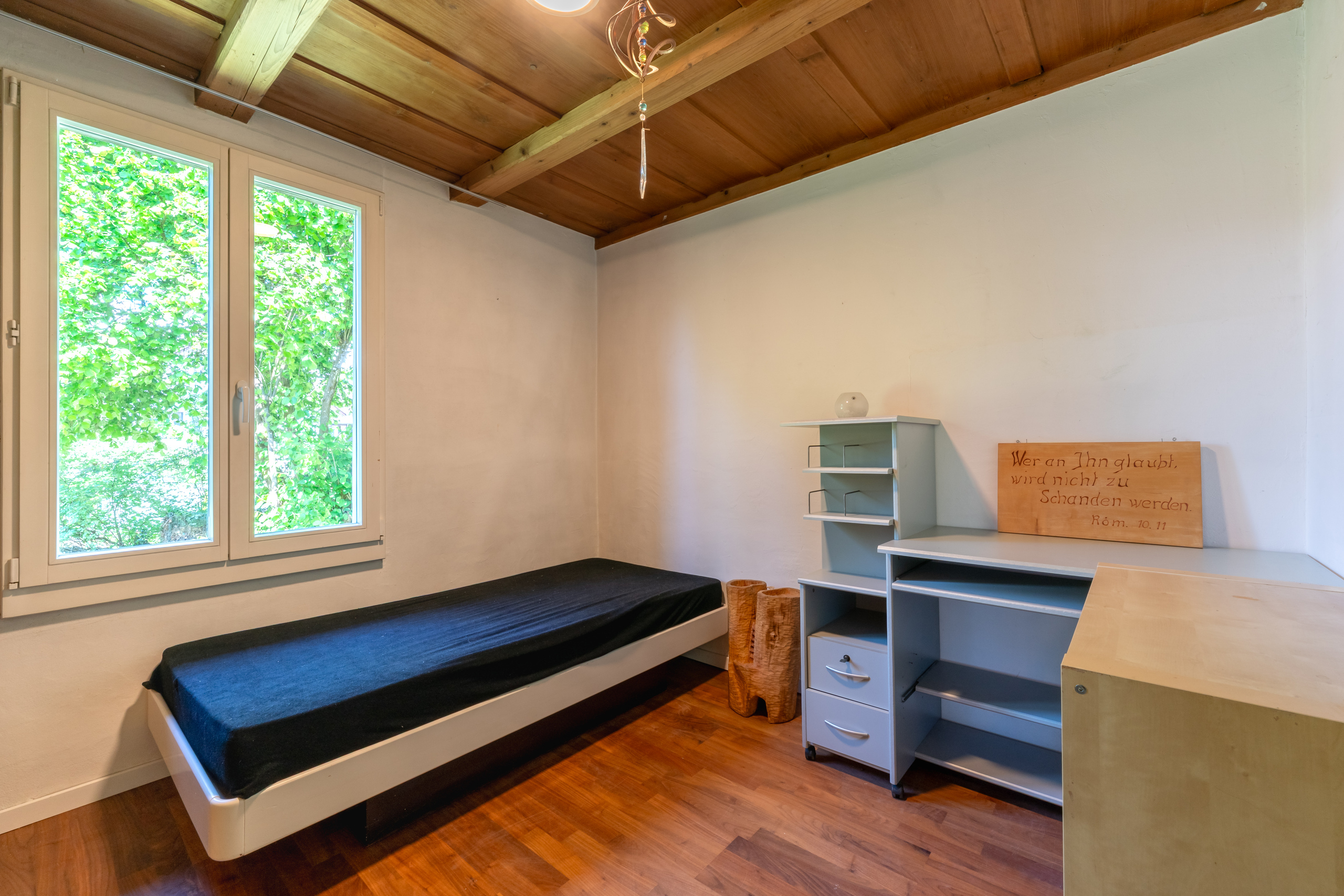 Helles Schlafzimmer mit Holzdecke und Blick ins Grüne