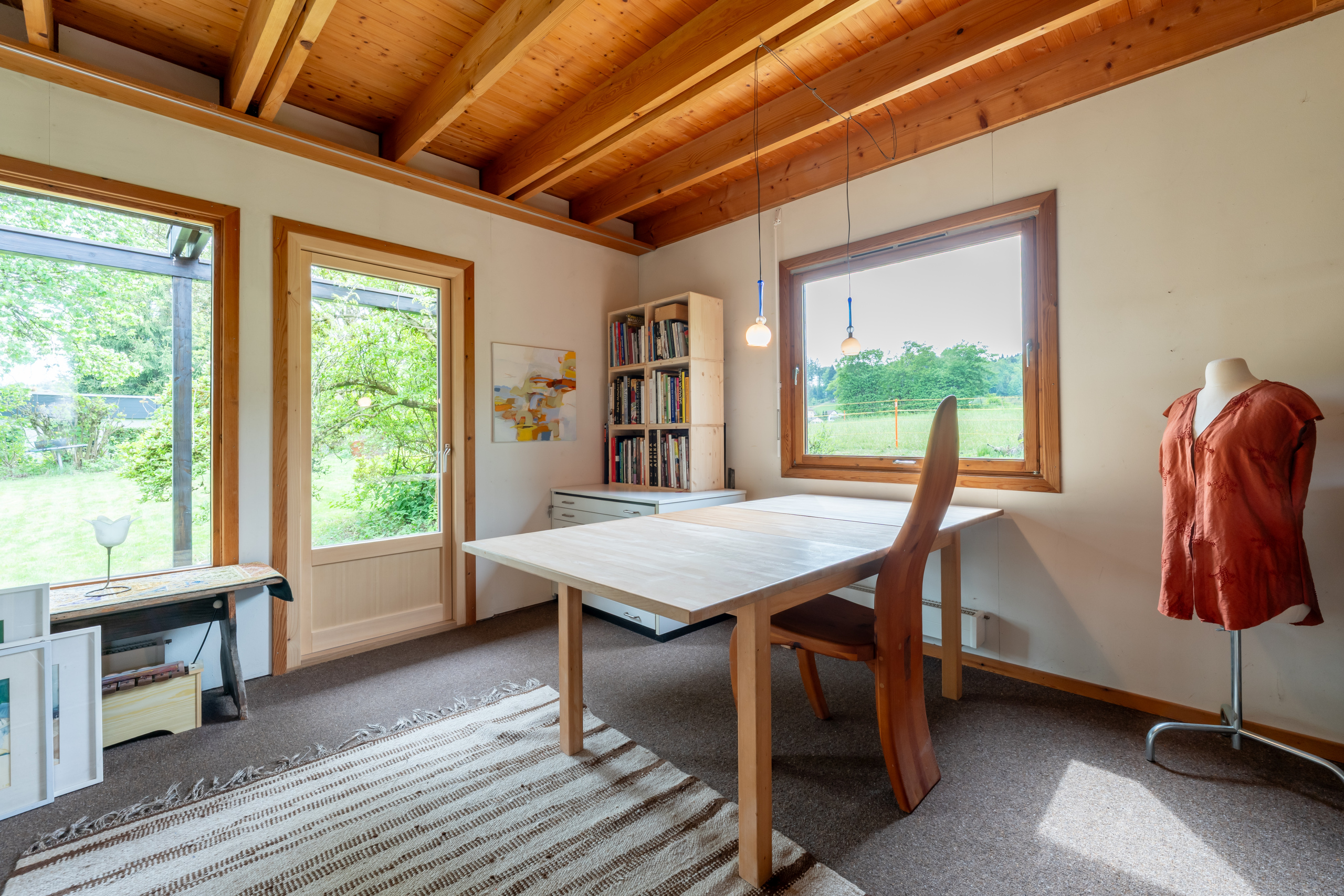 Helles Arbeitszimmer mit Holzdecke und Gartenblick