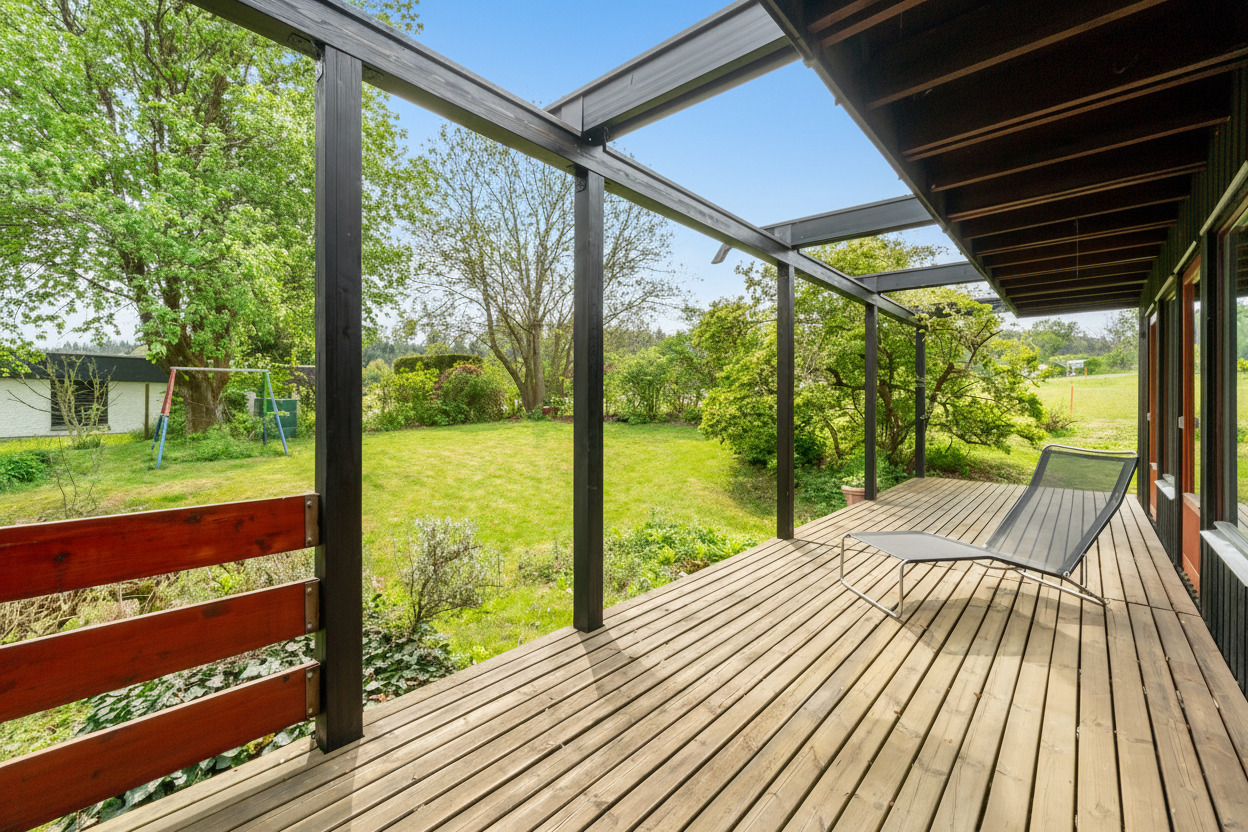 Überdachte Holzterrasse mit Gartenblick