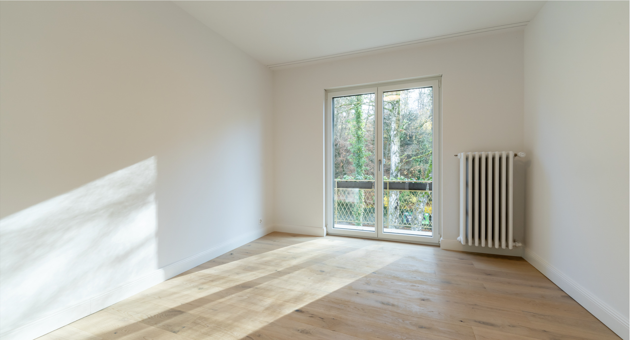 Heller leerer Raum mit Balkonfenster und Heizkörper