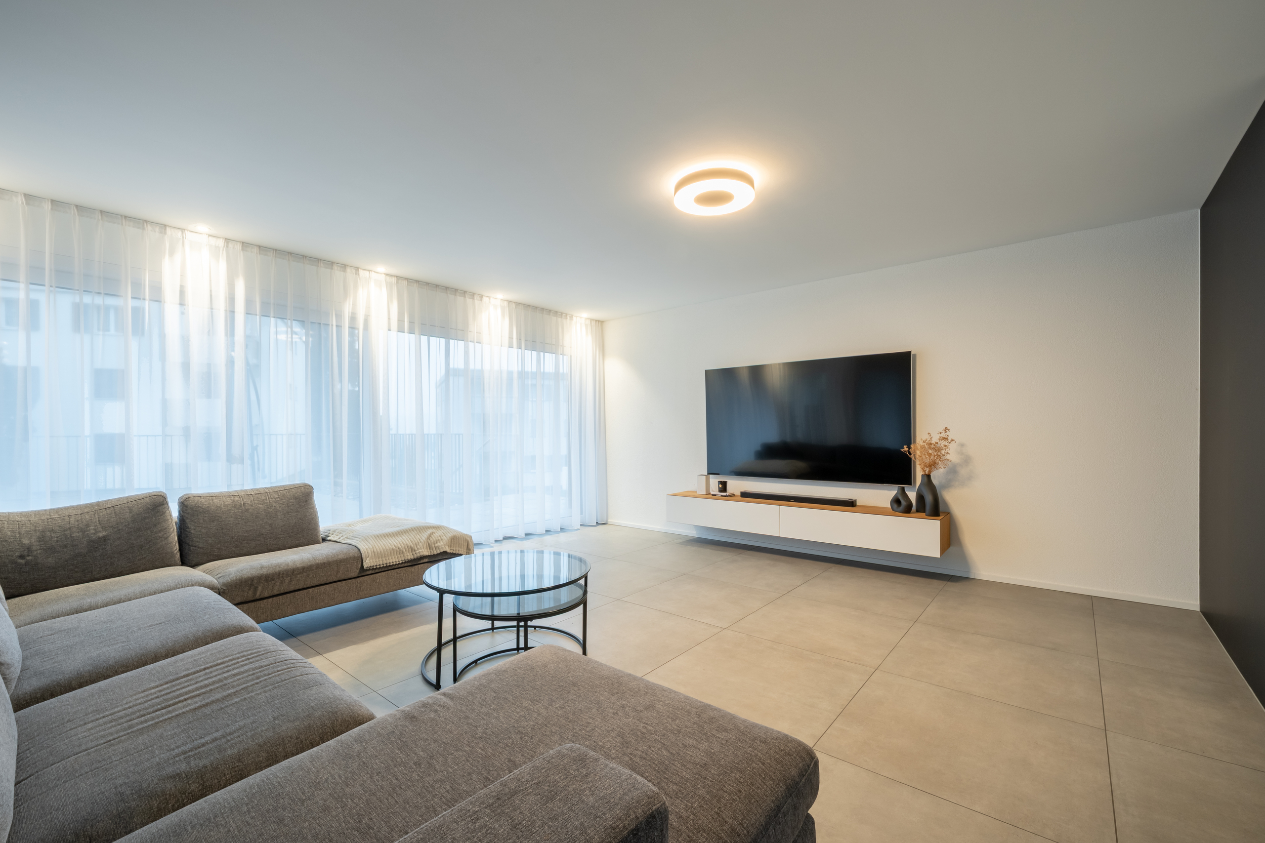 Heller moderner Wohnraum mit TV-Wand und Sofalandschaft