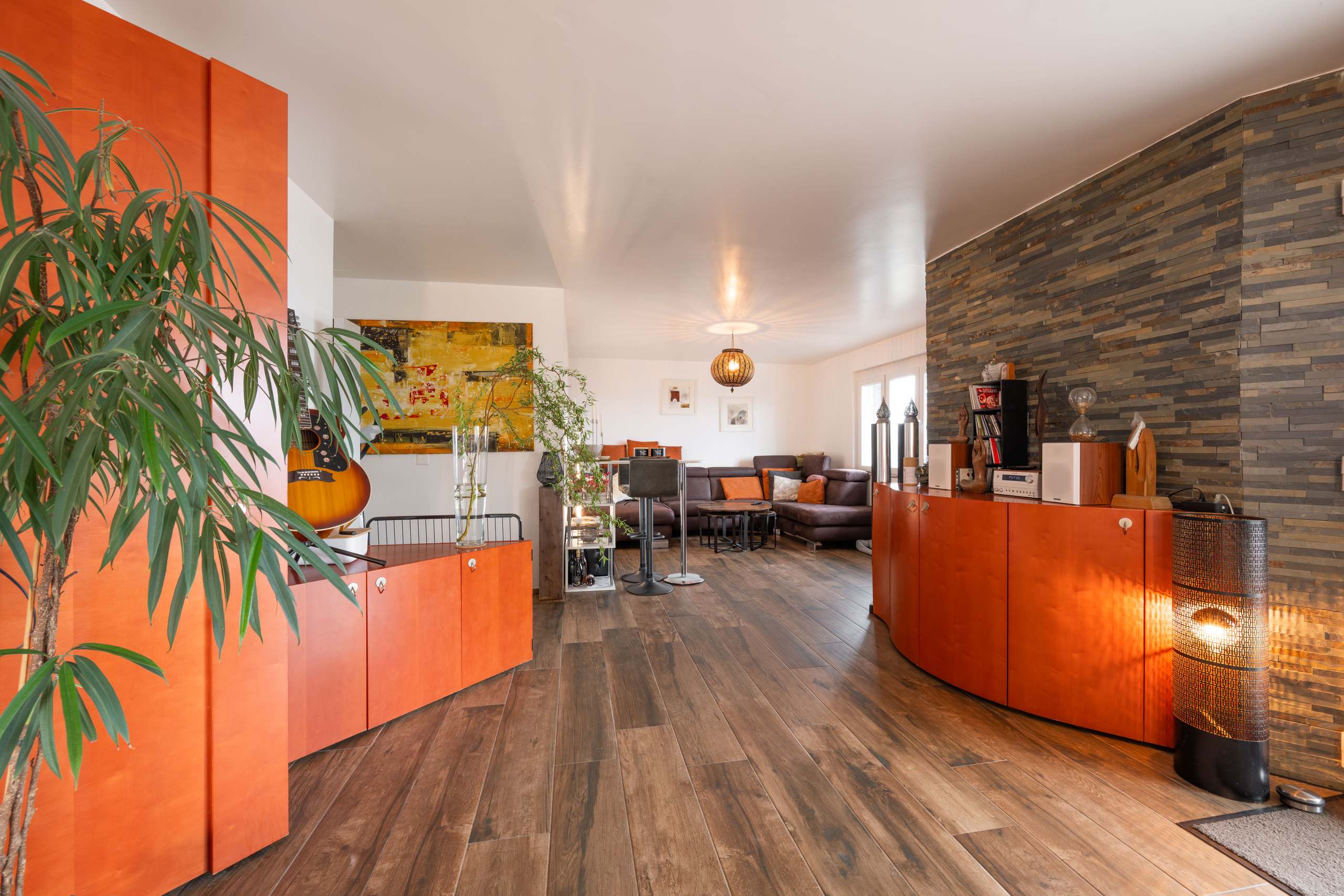 Großzügiges, modern gestaltetes Wohnzimmer mit Holzoptikboden und Akzentwand