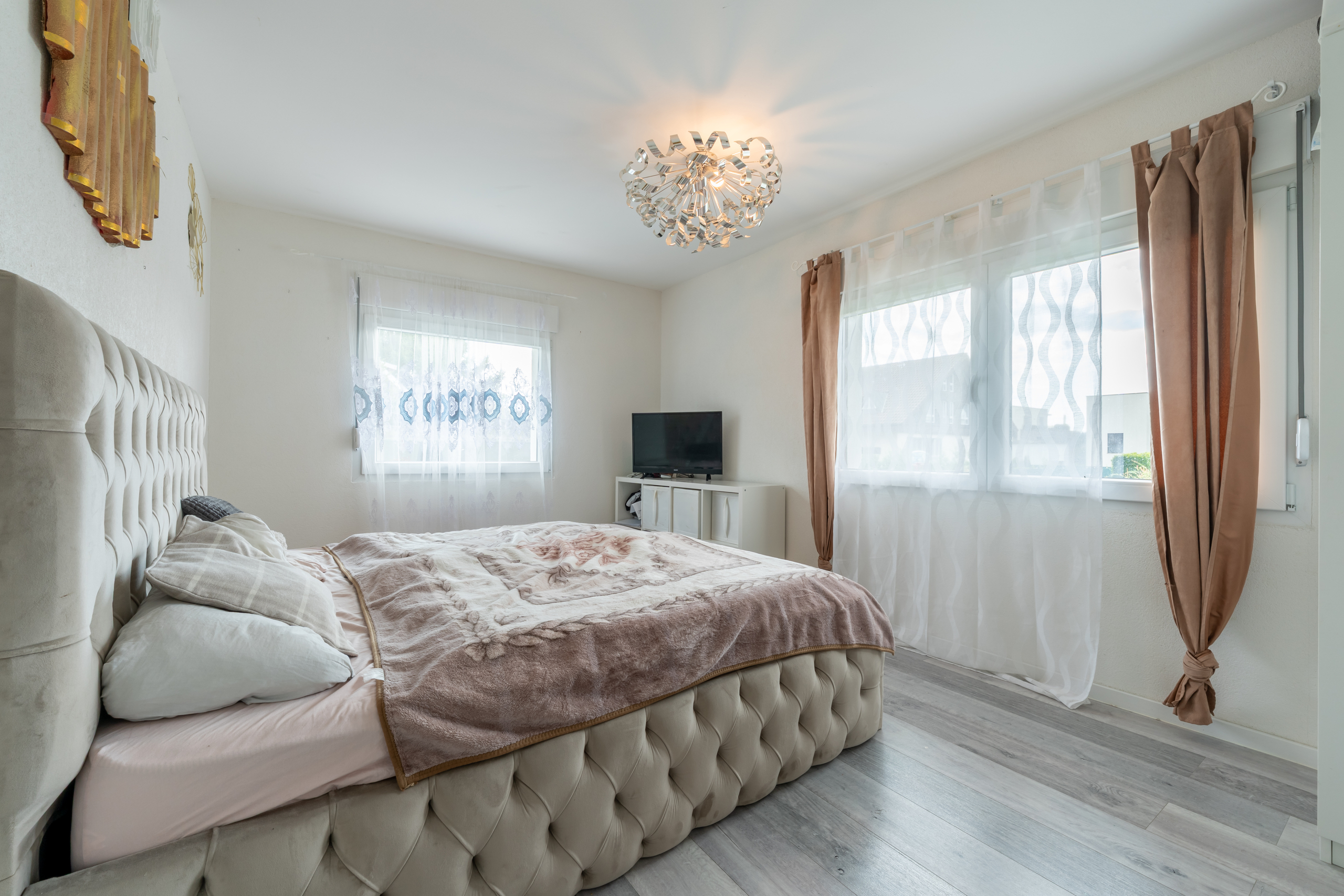Schlafzimmer mit großem Bett und hellen Vorhängen