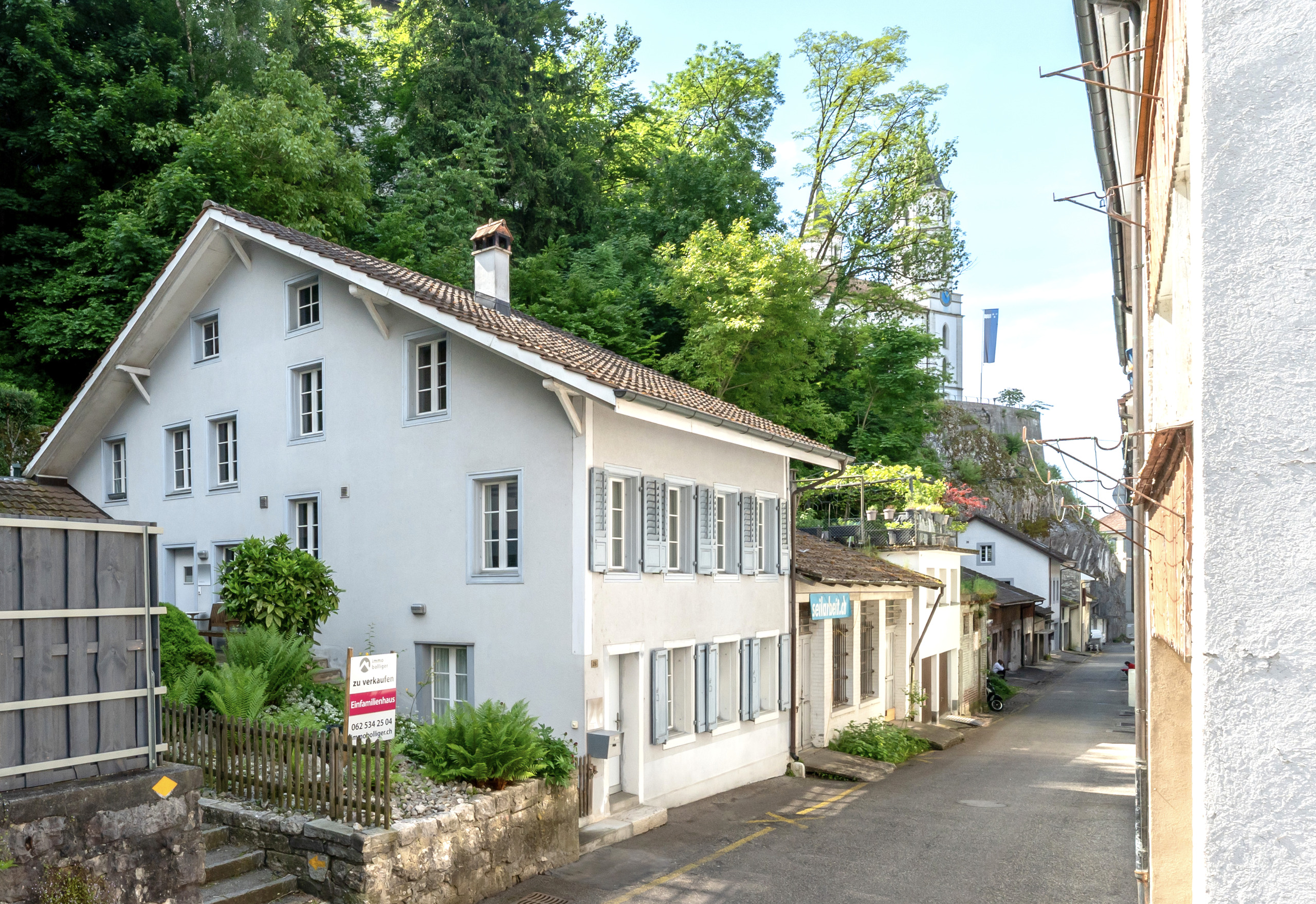 Helles Wohnhaus an schmaler Straße im Grünen