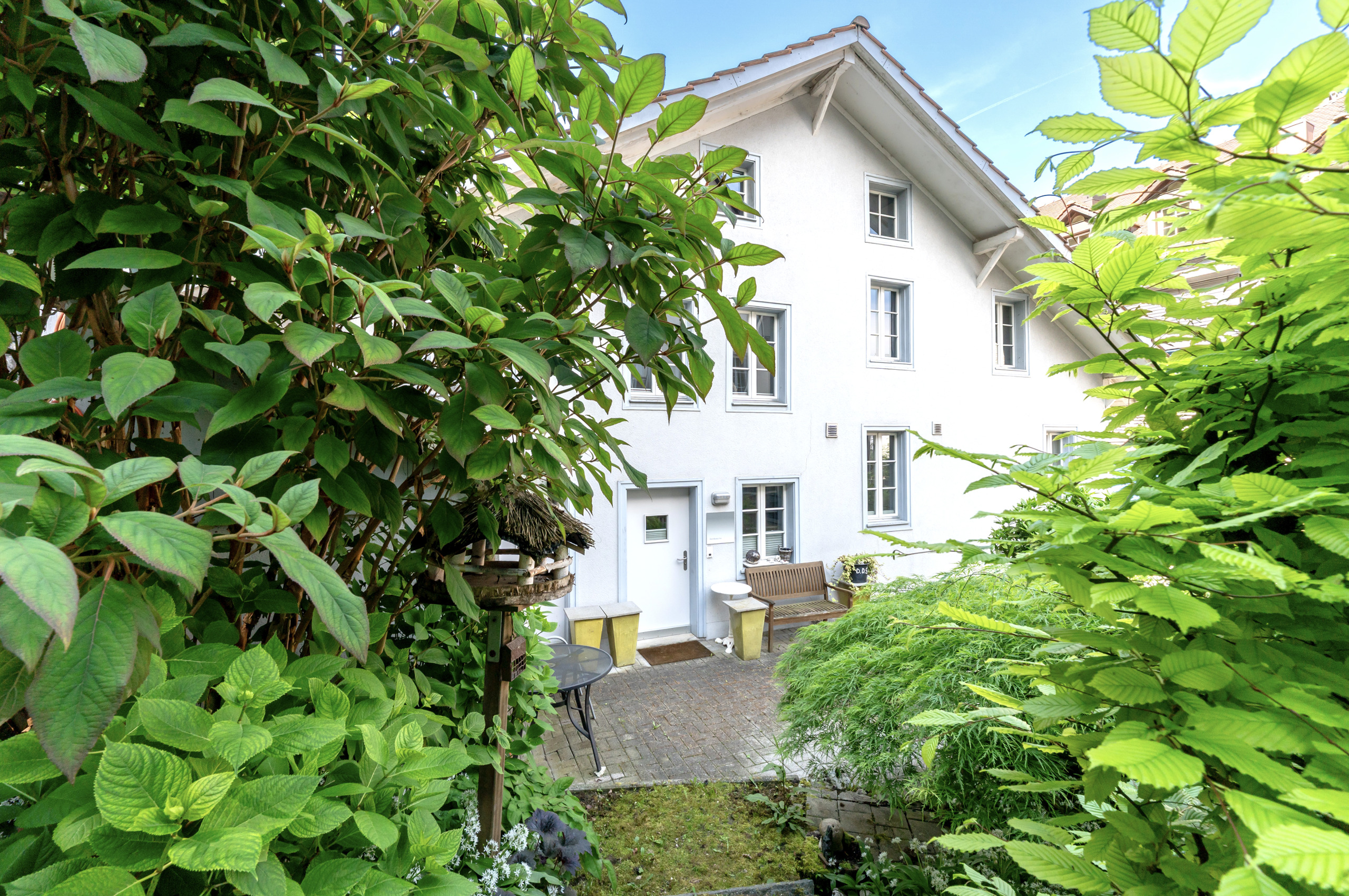 Außenansicht eines weiß verputzten Hauses mit Garten