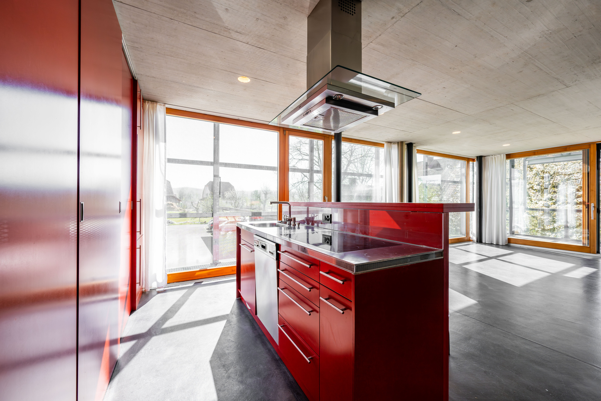 Moderne Küche mit roter Insel und großen Fensterflächen