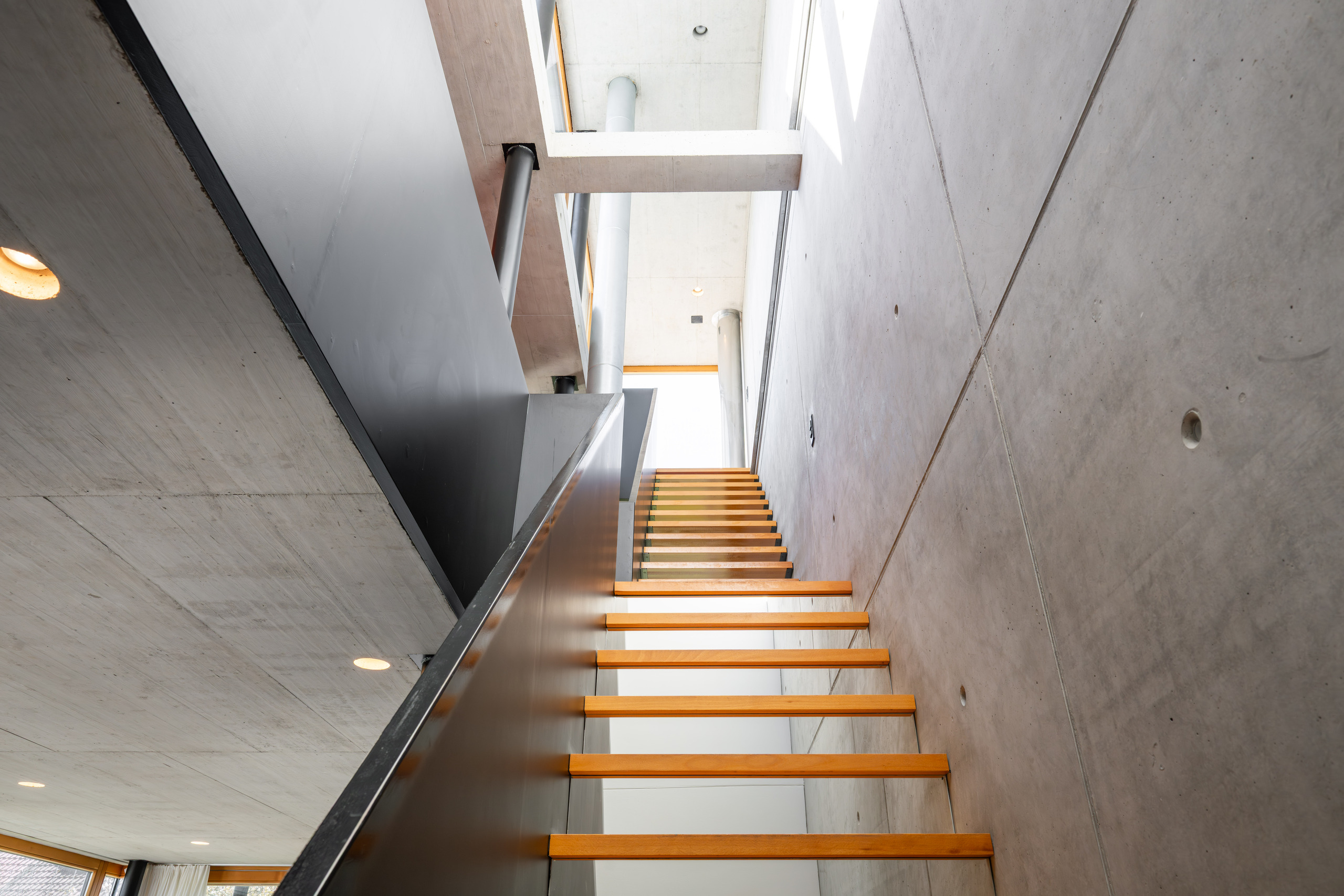 Moderne Betontreppe mit Holzstufen und Lichtschacht