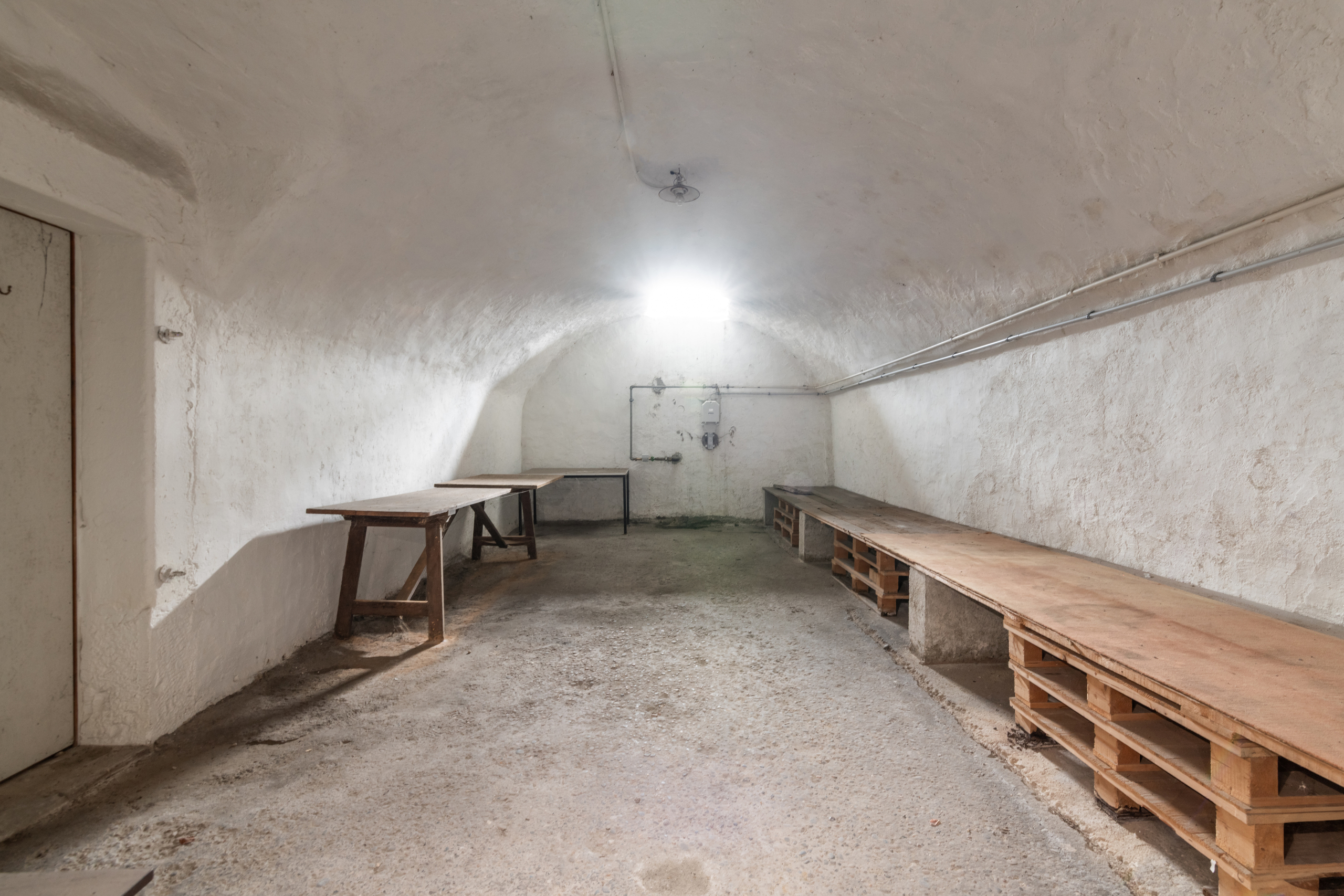 Gewölbter Kellerraum mit Arbeitstischen