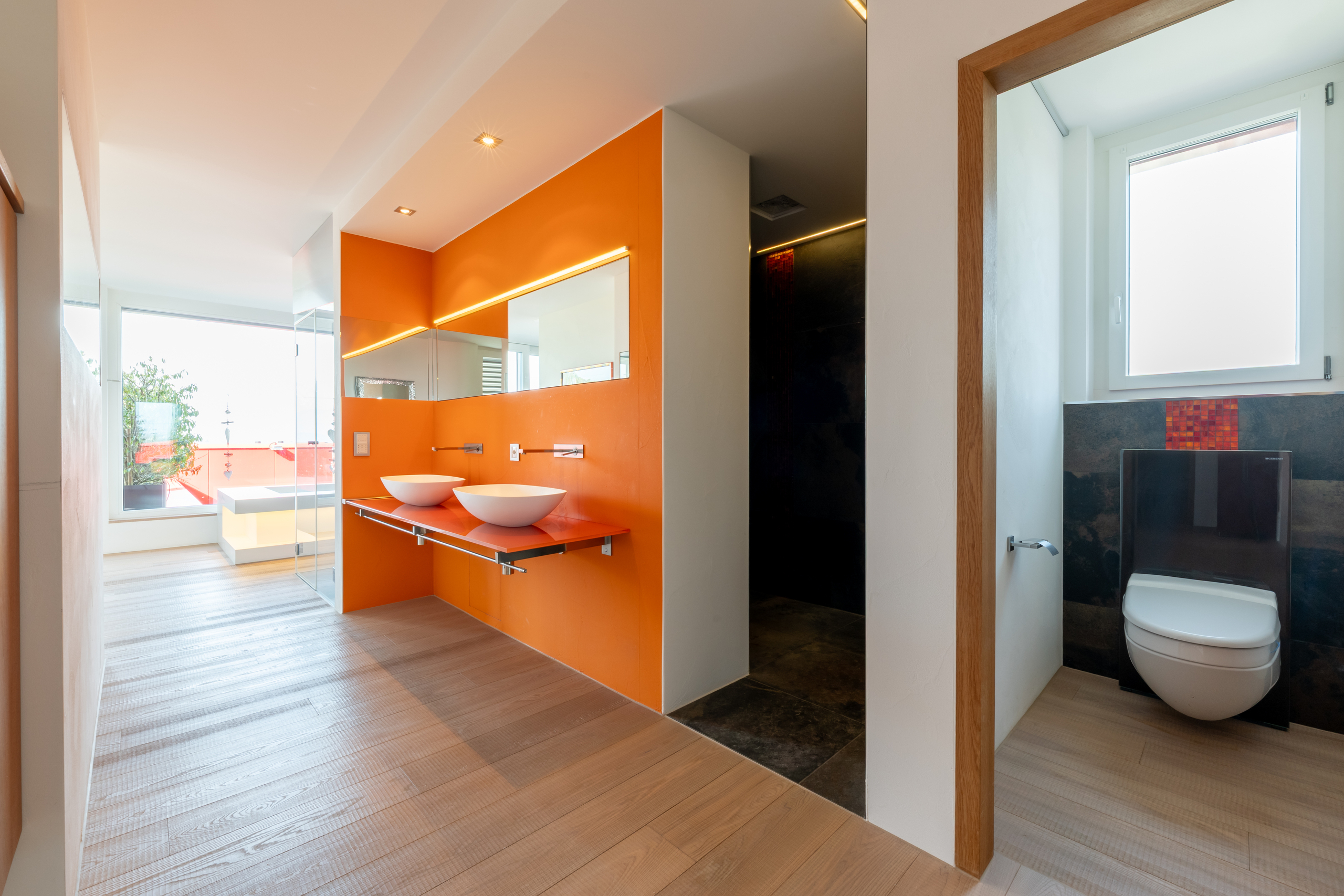 Modernes Bad mit separatem WC und orangefarbener Akzentwand