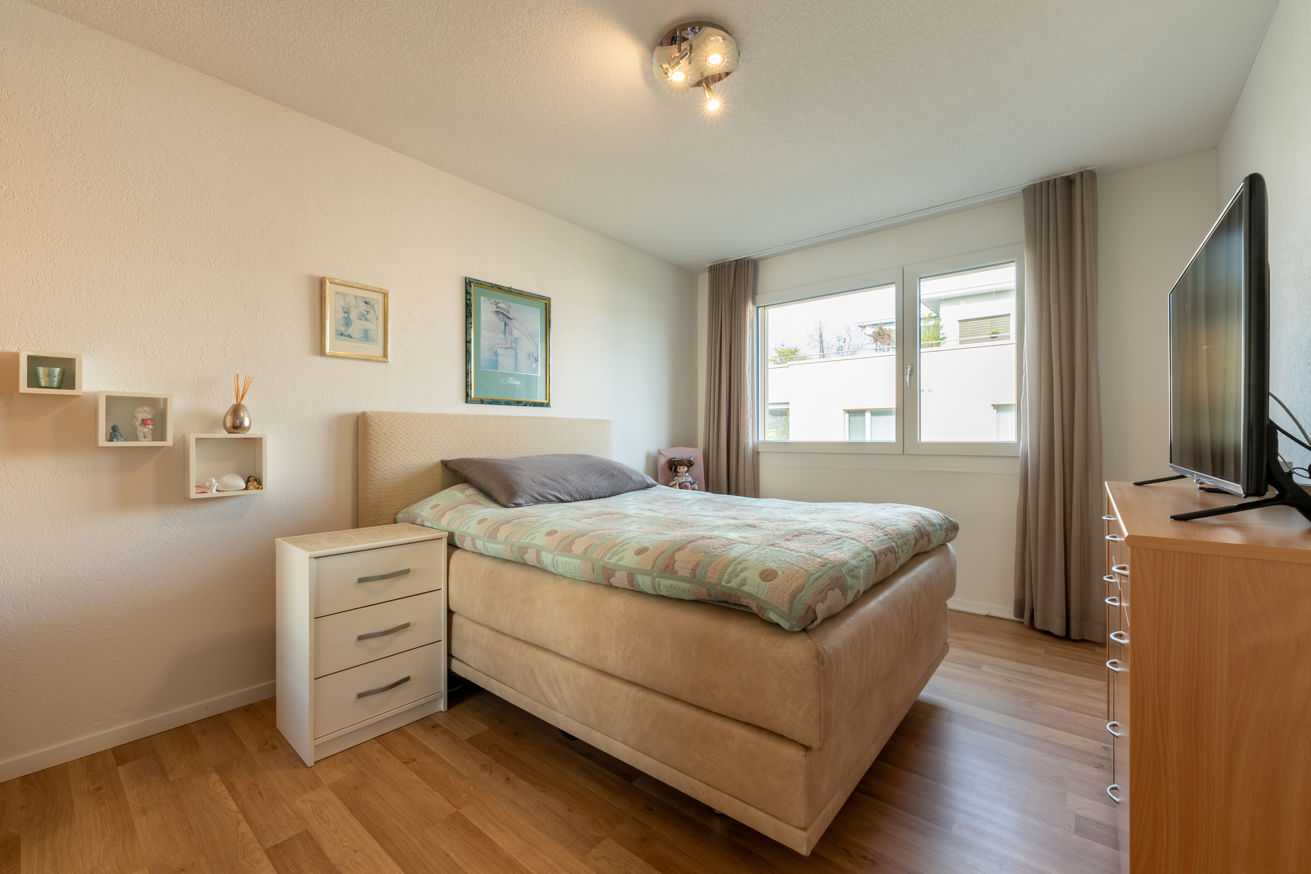 Helles Schlafzimmer mit Doppelbett und Fensterfront