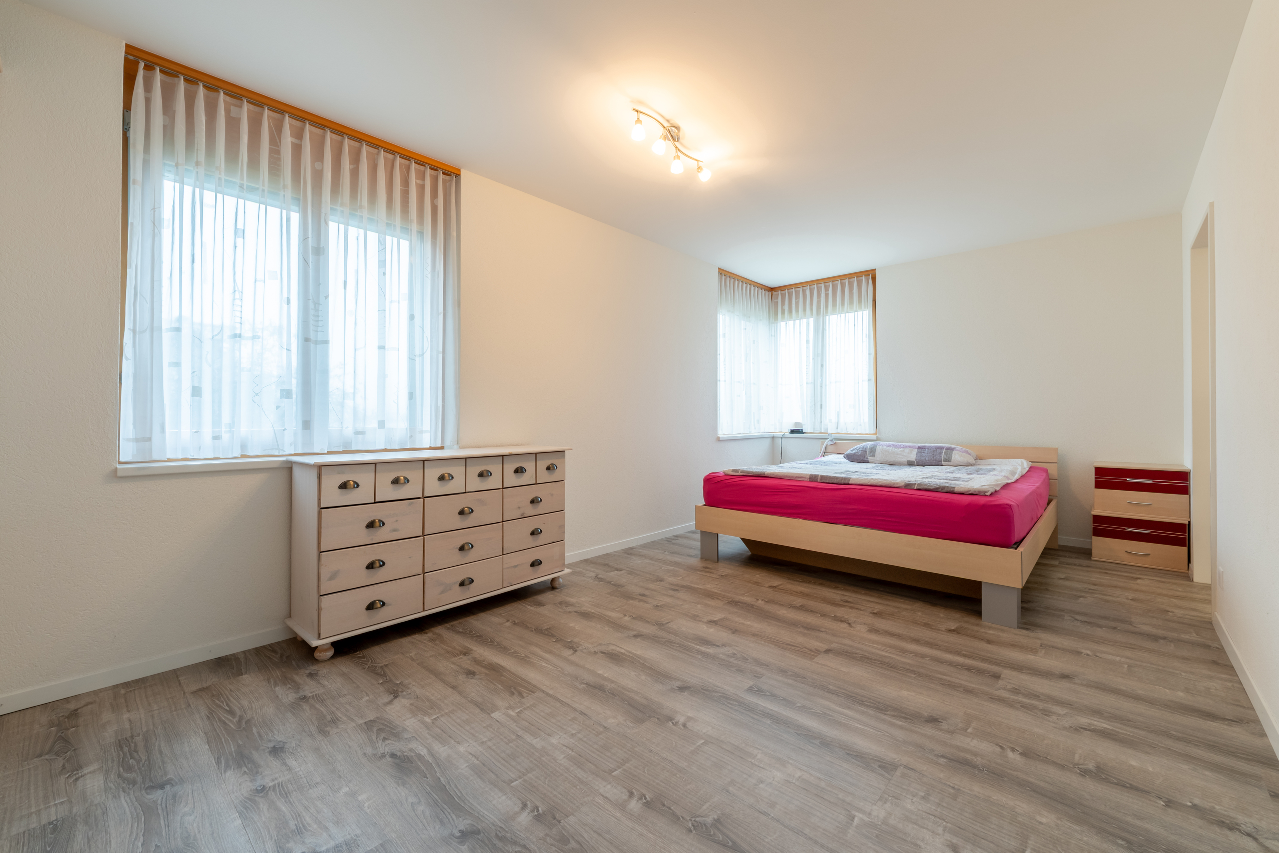 Helles Schlafzimmer mit zwei Fenstern und Bett