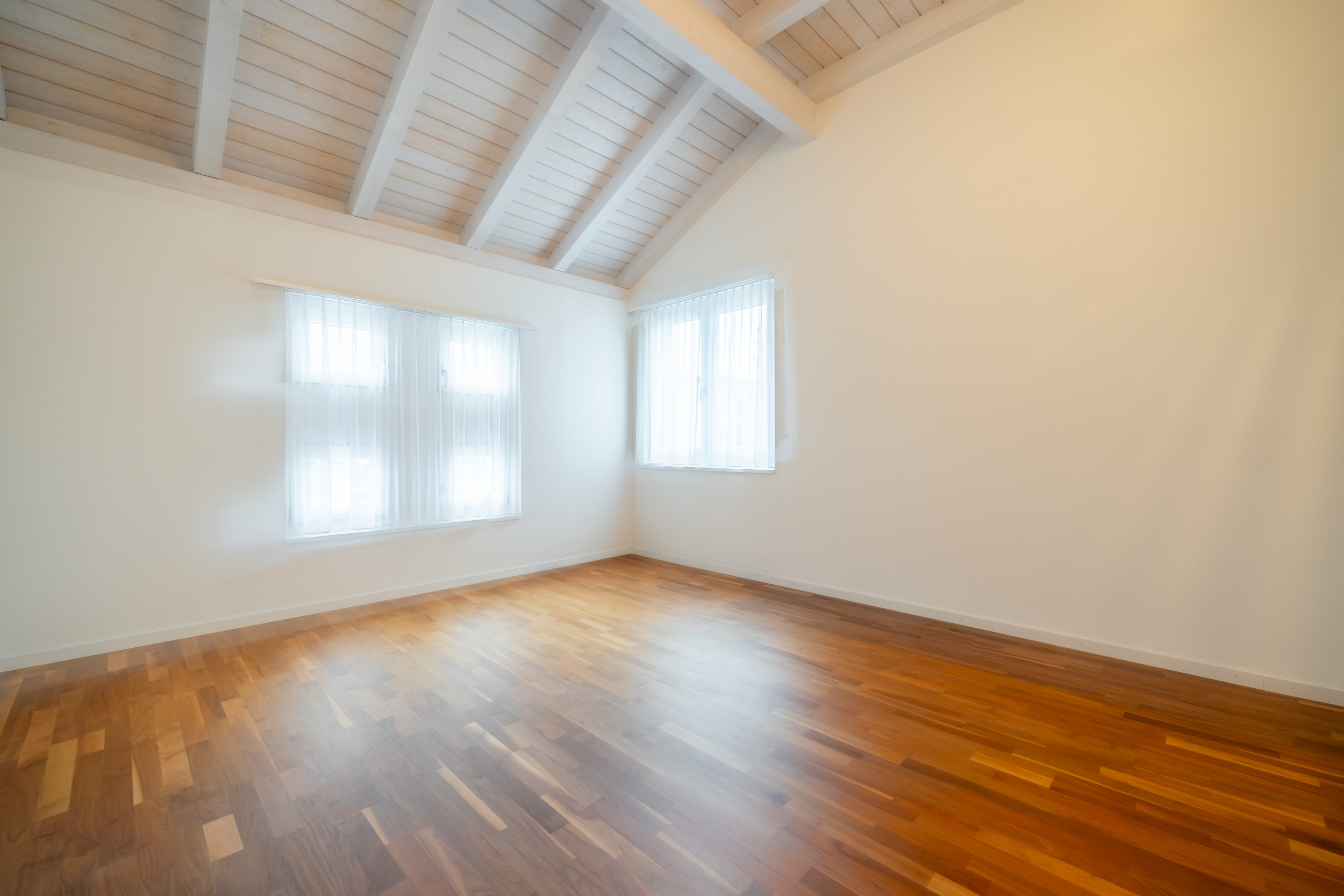Helles, leeres Zimmer mit sichtbarer Holzbalkendecke