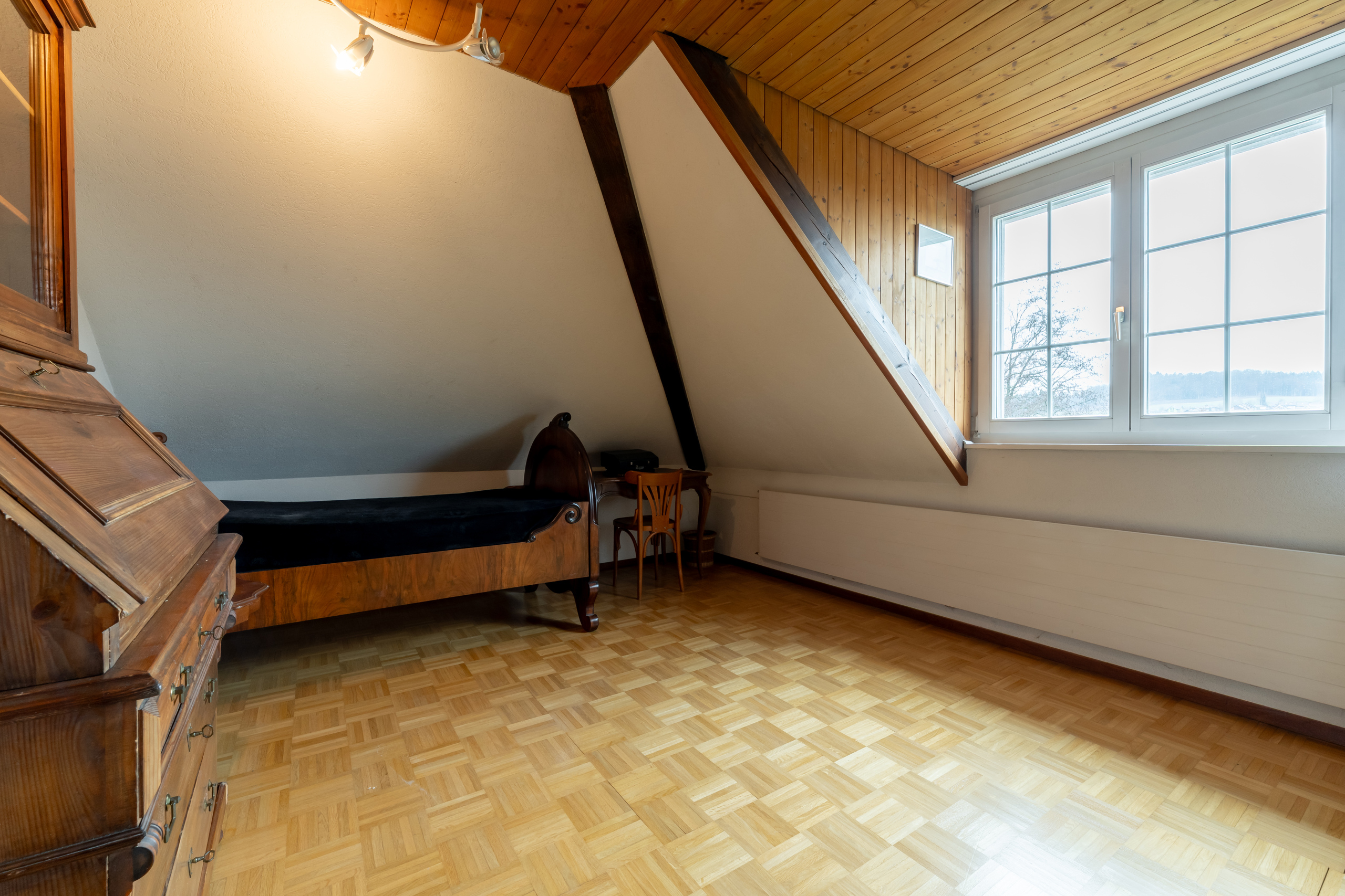 Dachgeschosszimmer mit Holzdecke und Sprossenfenster