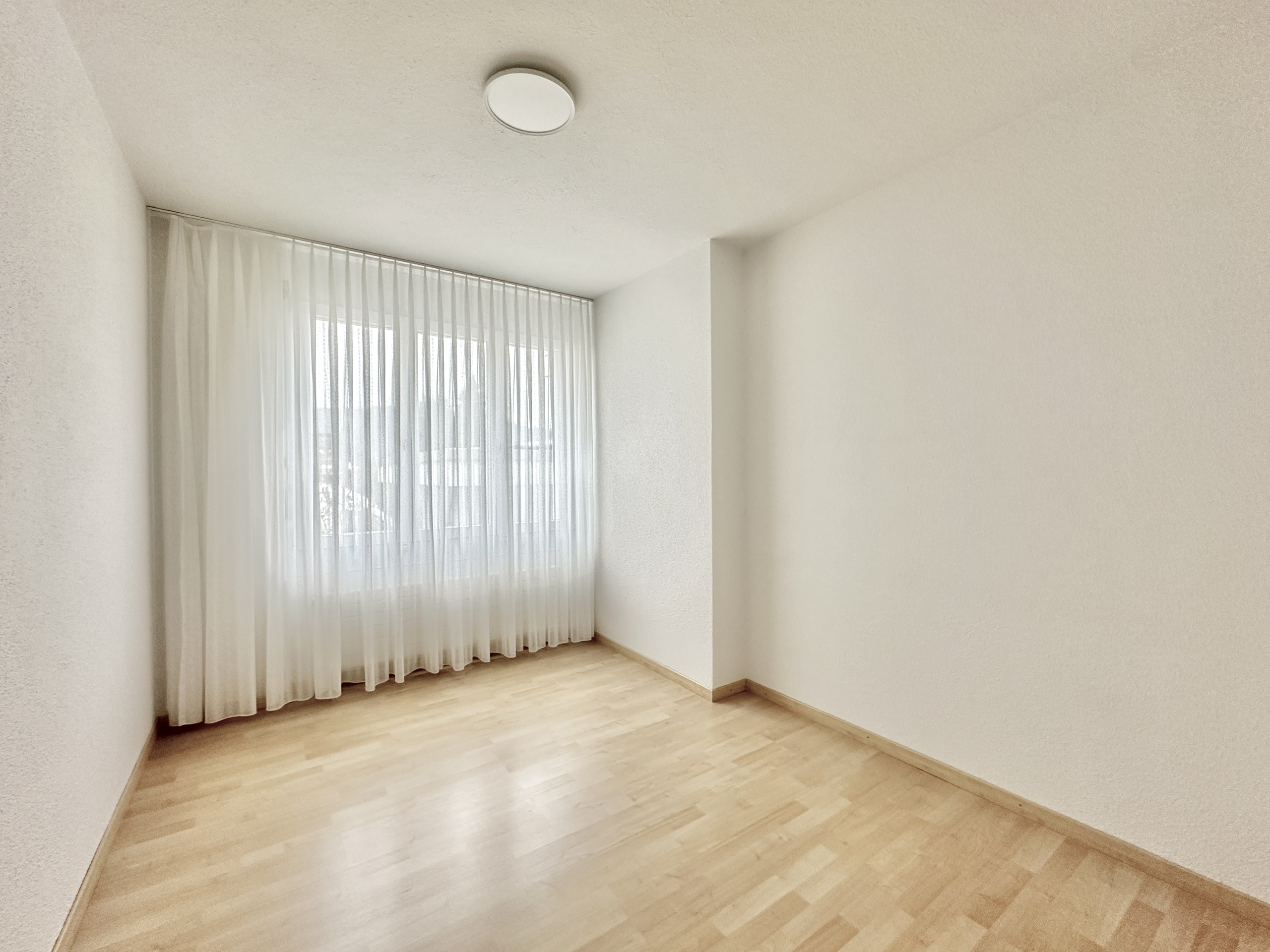 Leeres, helles Zimmer mit Fensterfront