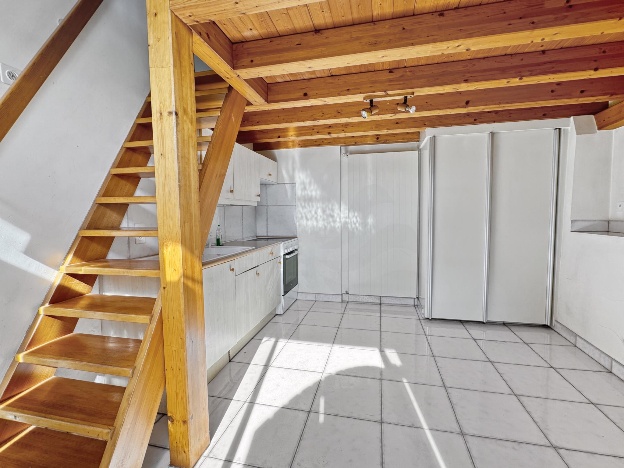 Kleine Küche mit Holztreppe und sichtbaren Balken