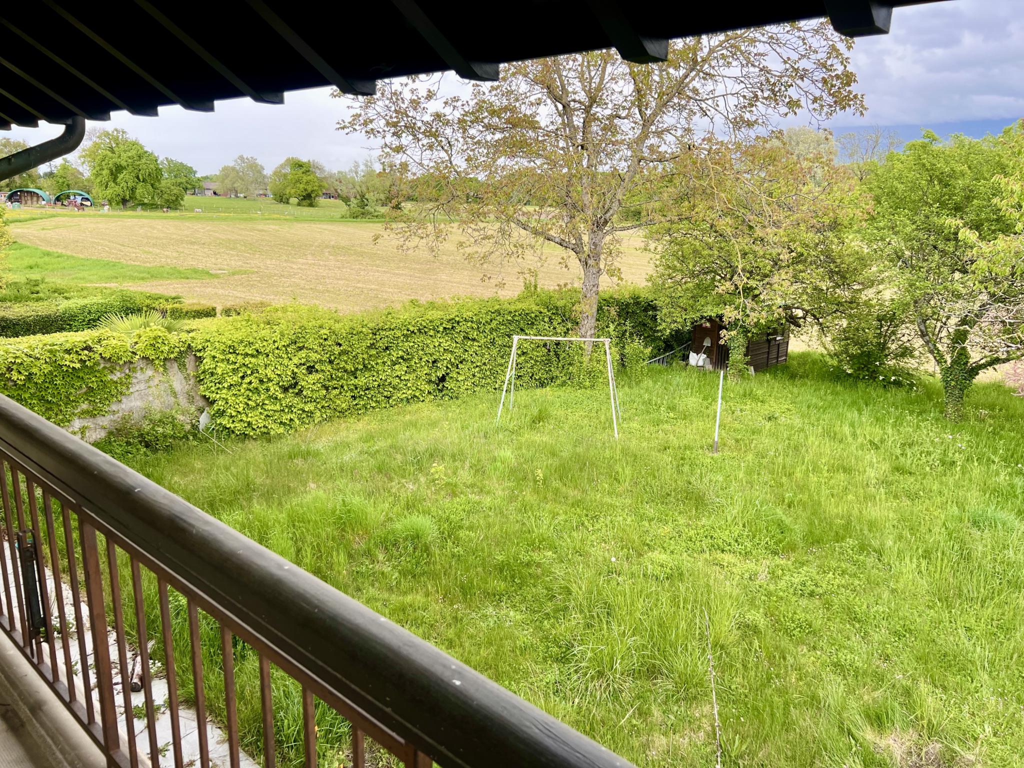 Blick vom Balkon auf einen großen Garten und Wiesen