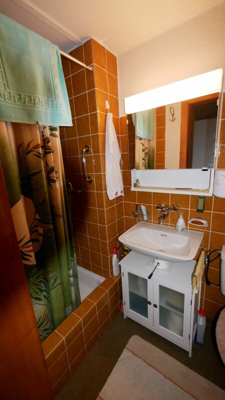 Kleines Badezimmer mit Badewanne und Waschtisch