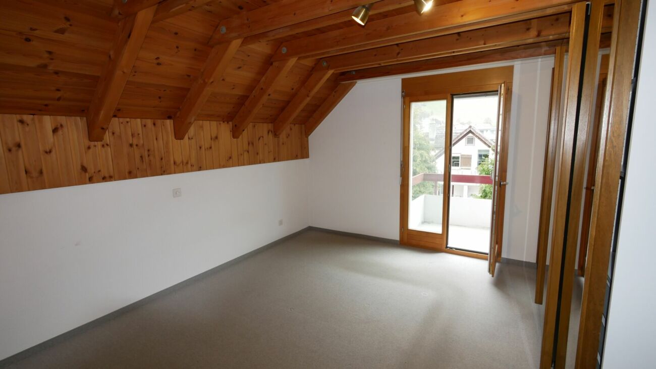Dachgeschossraum mit Holzverkleidung und Balkon