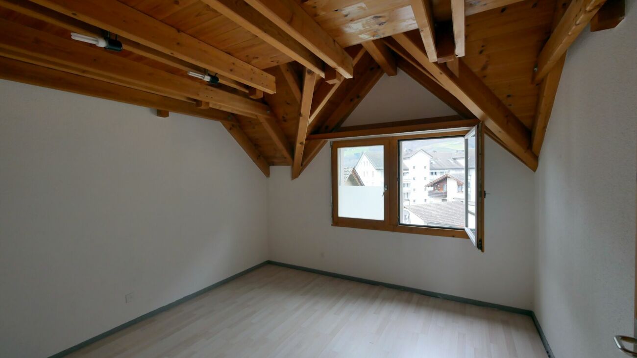 Dachzimmer mit Holzbalken und Fenster