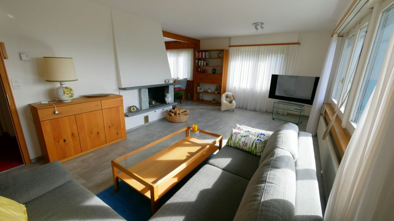 Helles Wohnzimmer mit Kamin und großen Fenstern