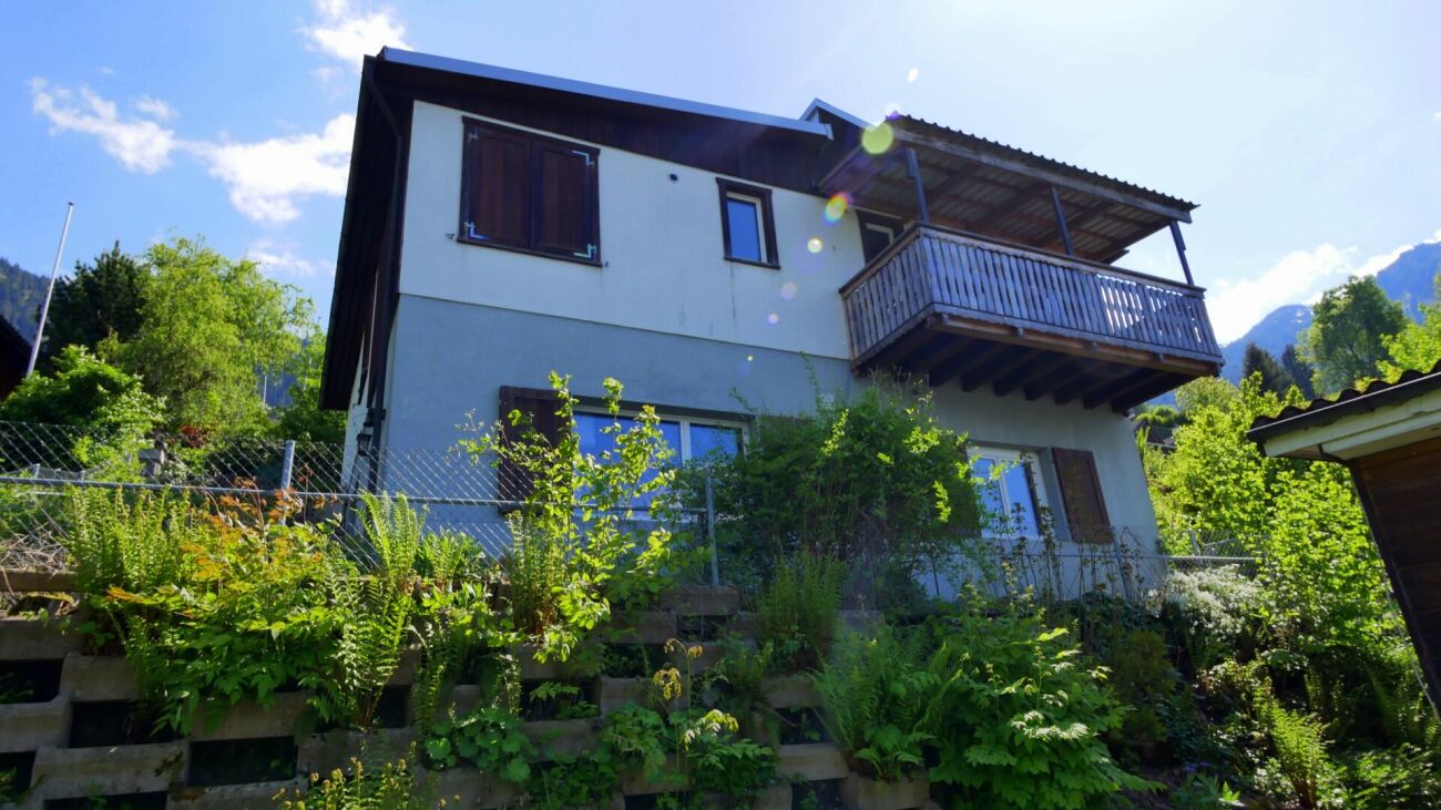 Haus mit Balkon und üppiger Bepflanzung