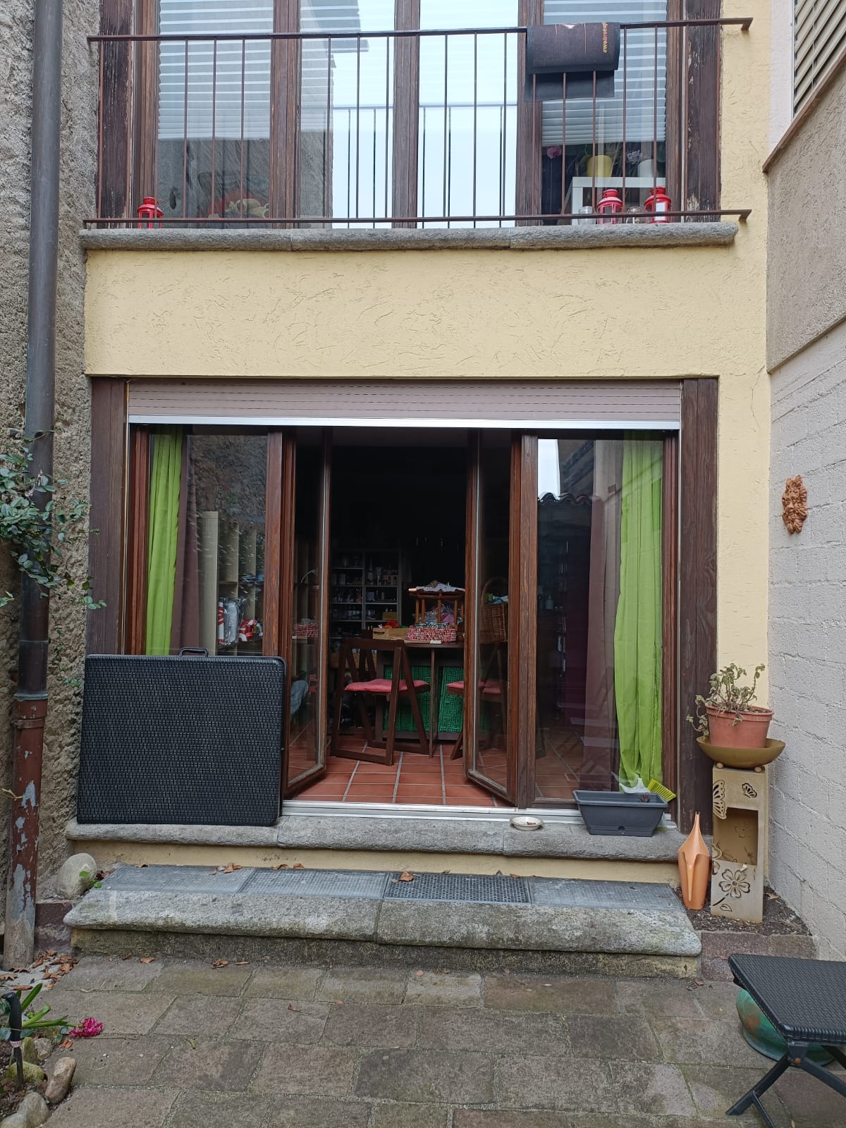Blick auf eine kleine Terrasse mit bodentiefen Fenstern und offenem Zugang zum Innenraum