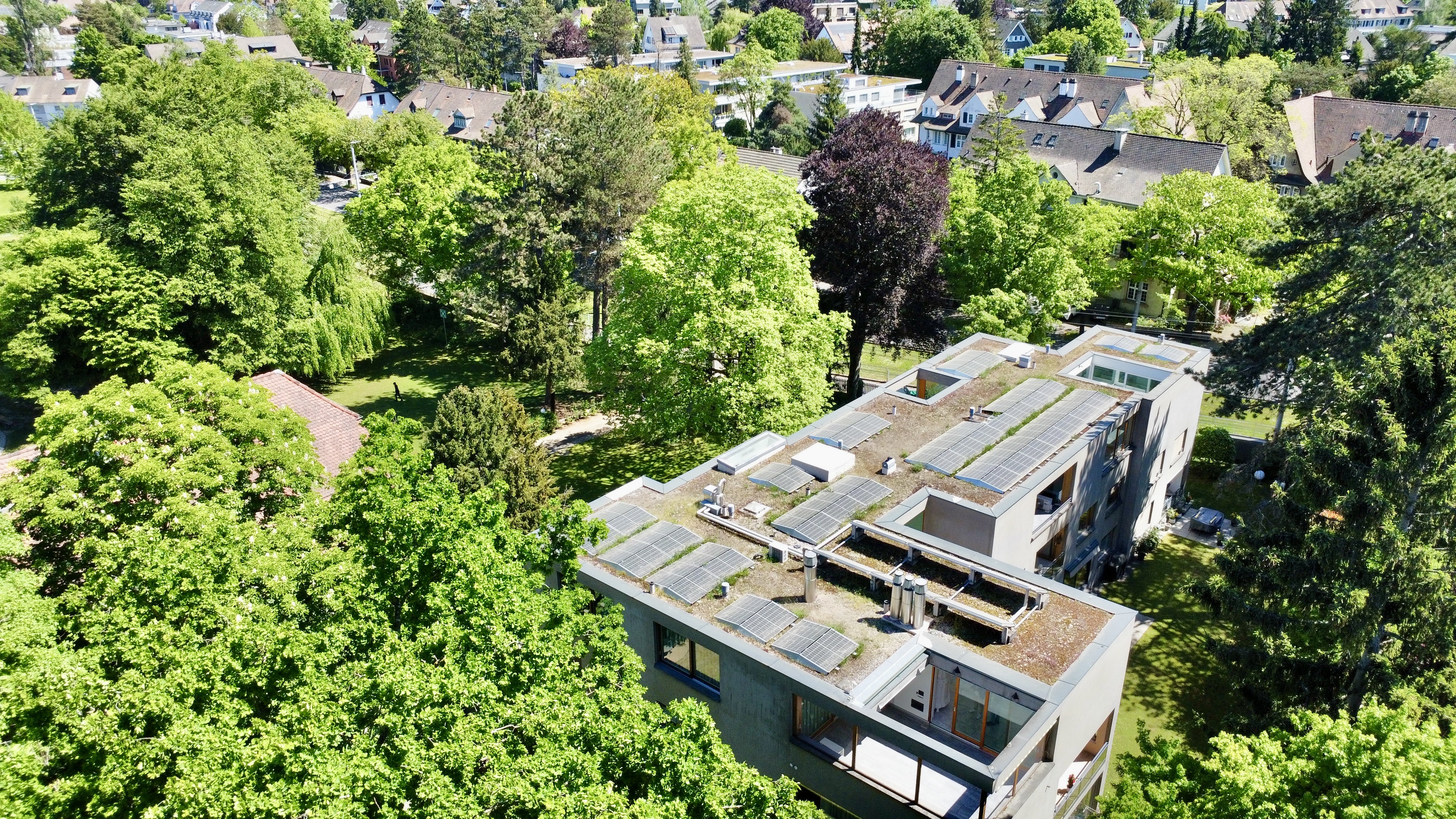 Luftaufnahme eines modernen Gebäudes mit begrüntem Flachdach und Solarmodulen